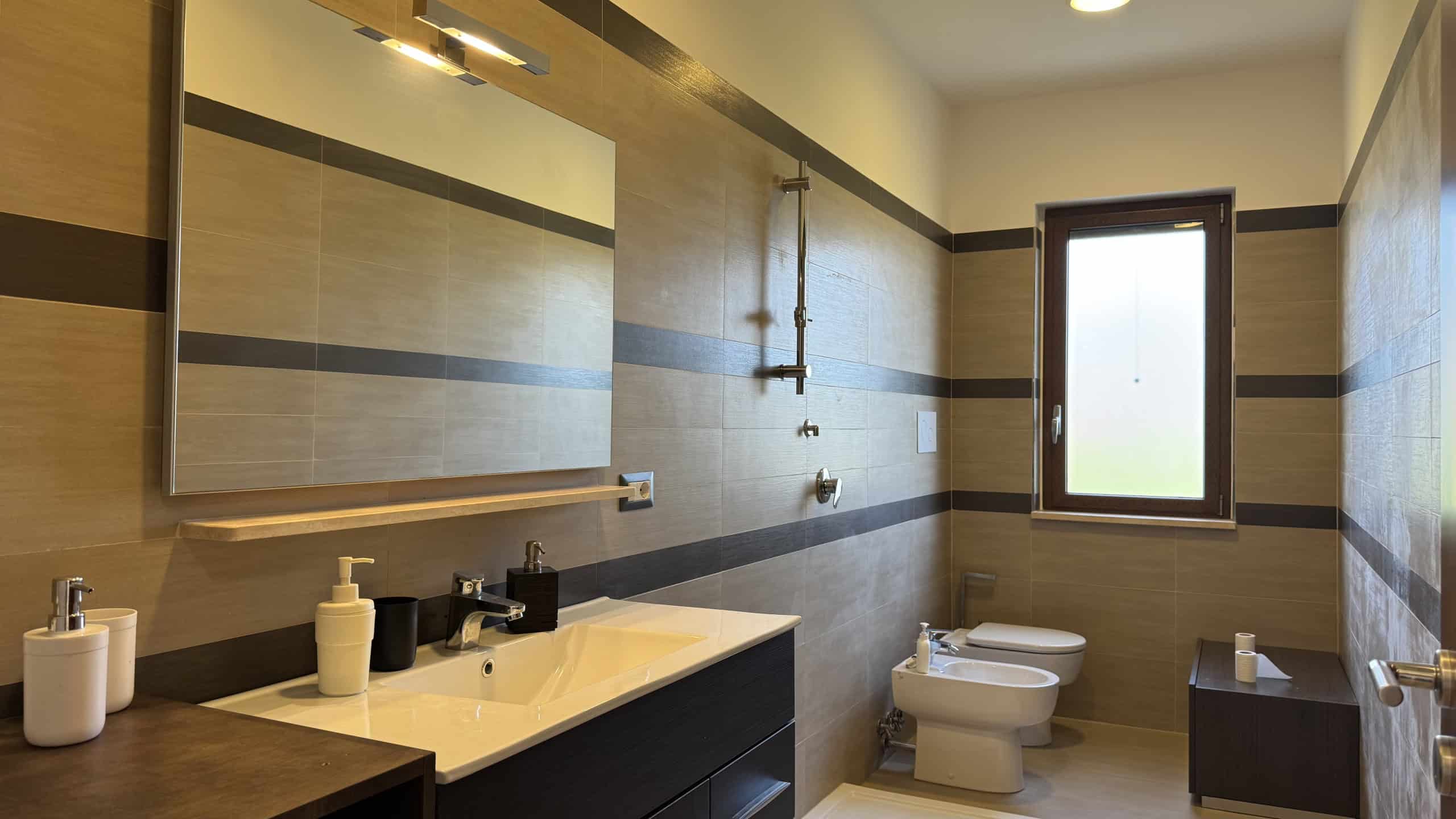 Bagno moderno con lavabo, specchio e finestra in villa unifamiliare in Contrada Rosa Isolera 7, Corriolo, Me.