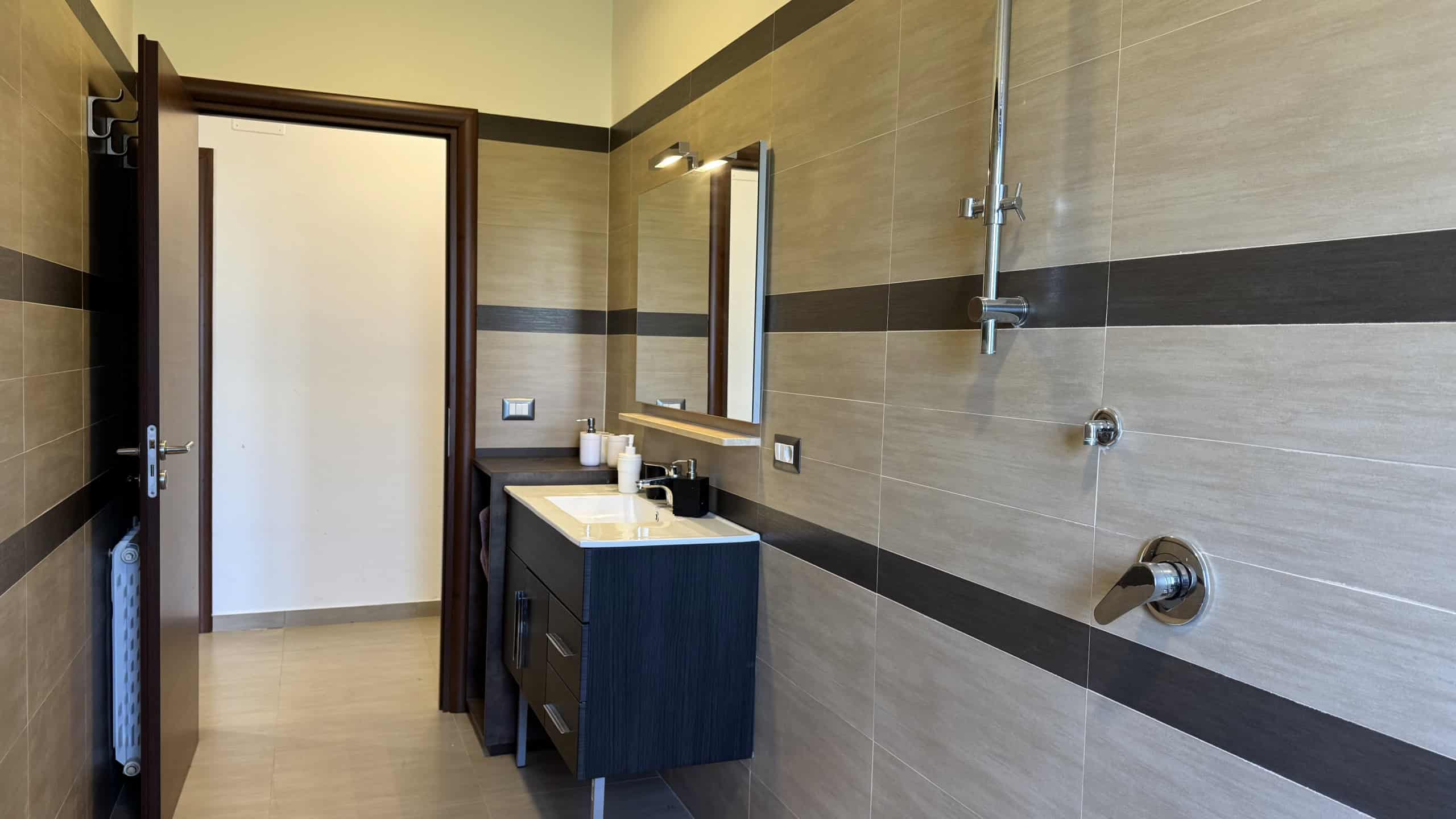 Bagno elegante con lavabo, specchio e doccia in una villa unifamiliare in vendita a Corriolo, Me.