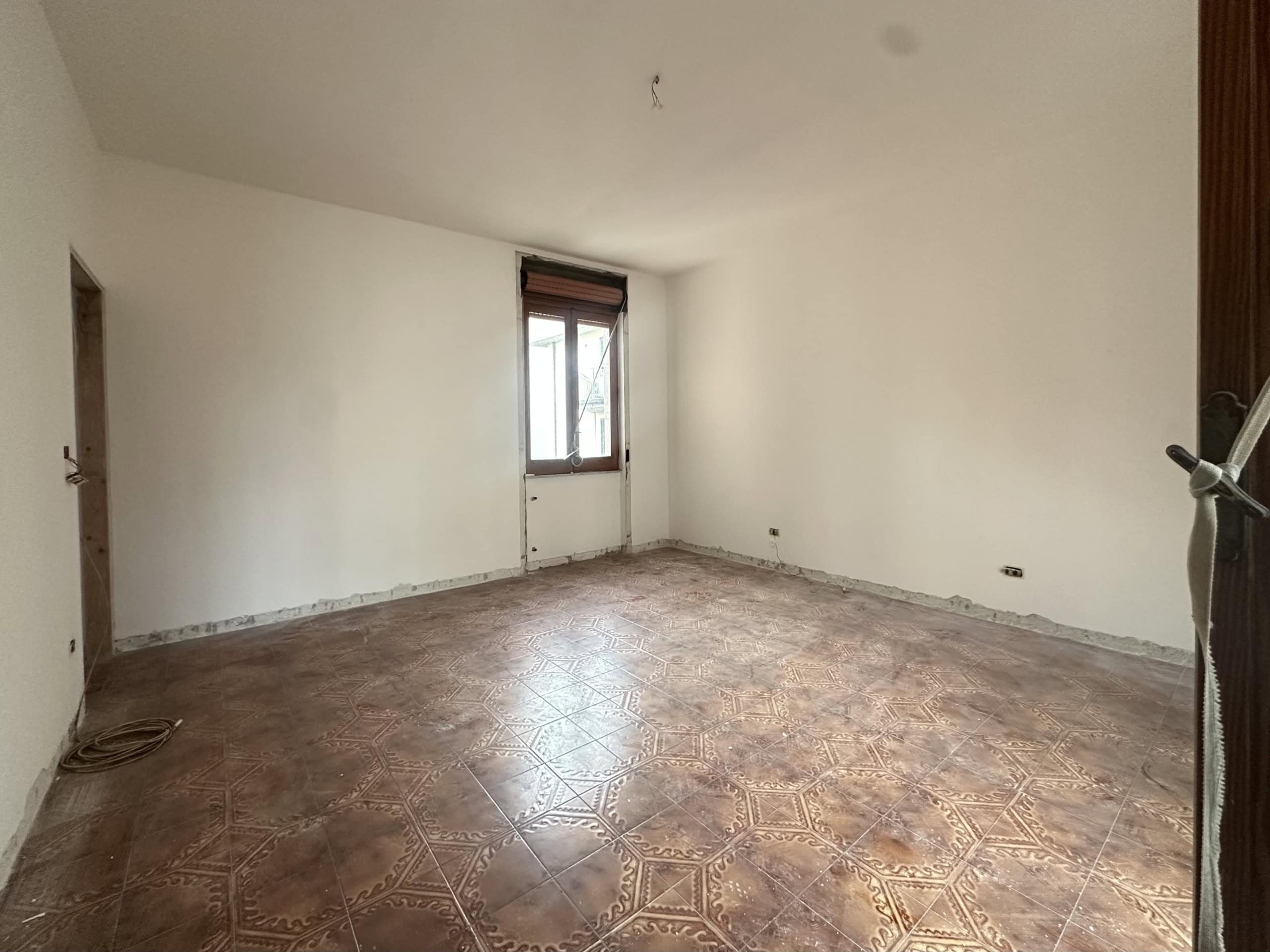 Ampio spazio interno di una stanza vuota con pareti bianche e finestra, pronta per essere personalizzata.