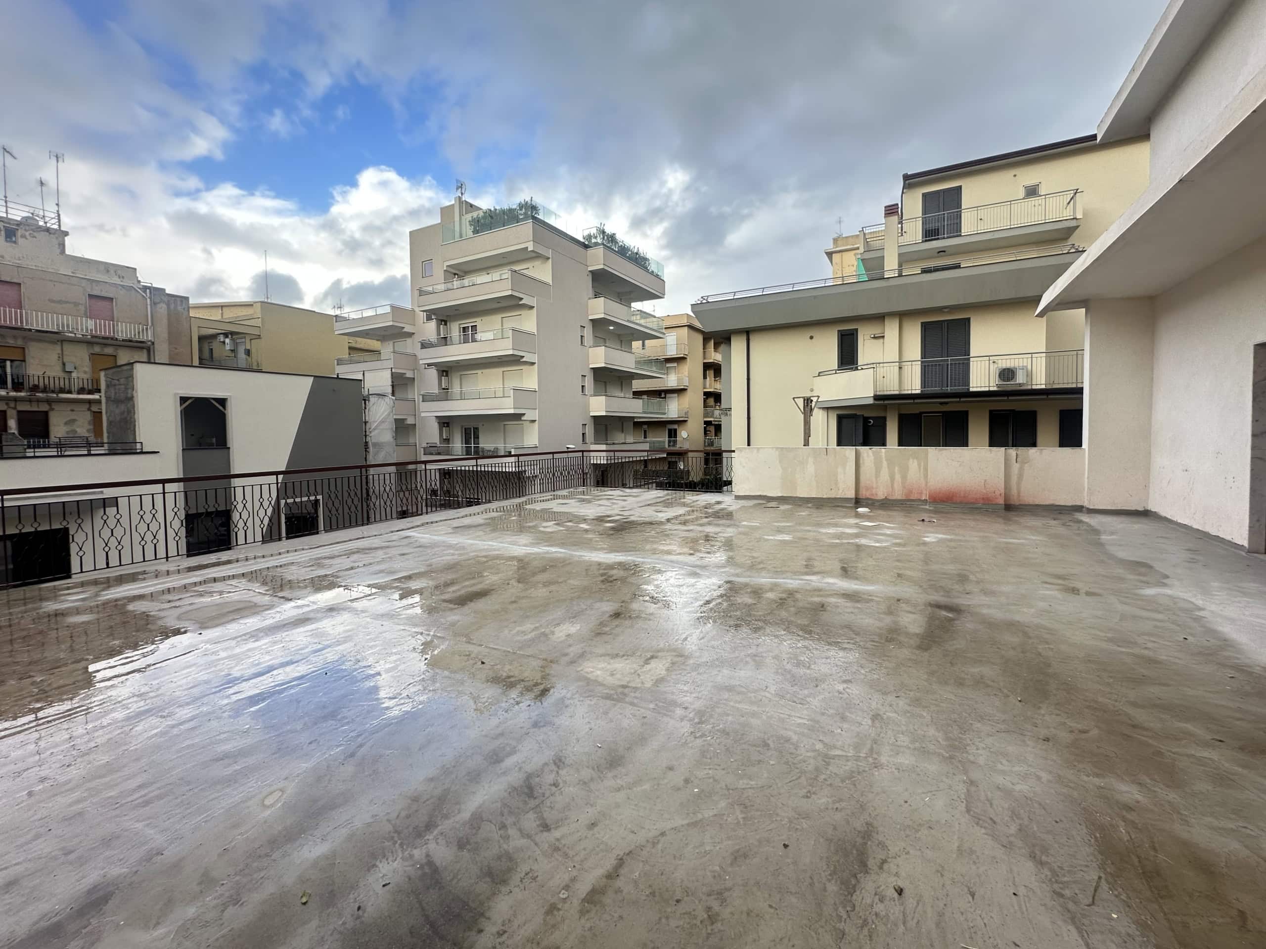 Terrazza panoramica con vista sulla città e cielo nuvoloso, ideale per relax e socializzazione all'aperto.
