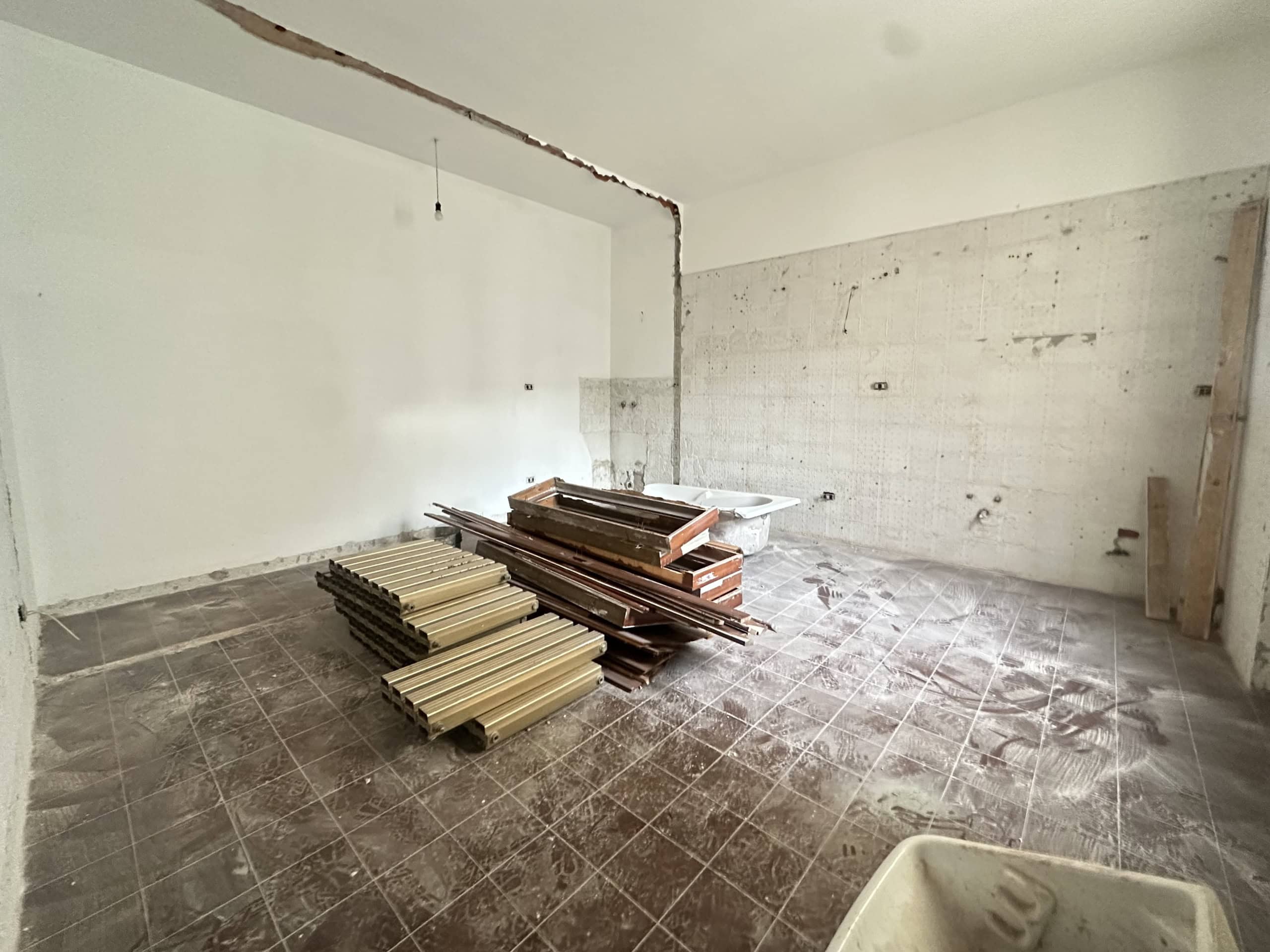 Interno di un appartamento in fase di ristrutturazione con materiali edili e pareti in fase di lavorazione.