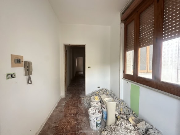 Balcone in fase di ristrutturazione con materiali e attrezzi, vista sulla città, illuminato dalla luce naturale, pronto per essere rinnovato.