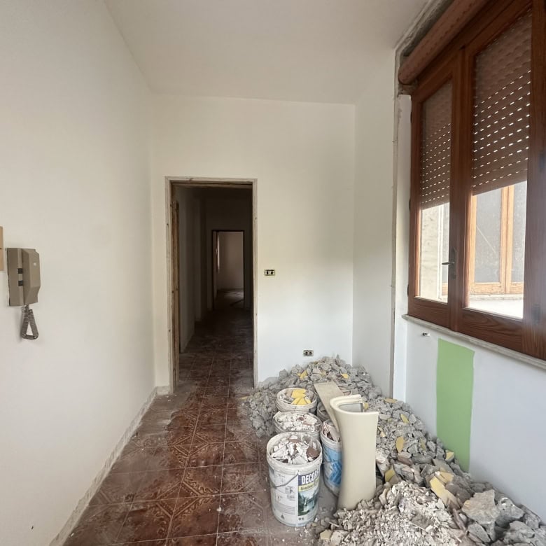Balcone in fase di ristrutturazione con materiali e attrezzi, vista sulla città, illuminato dalla luce naturale, pronto per essere rinnovato.