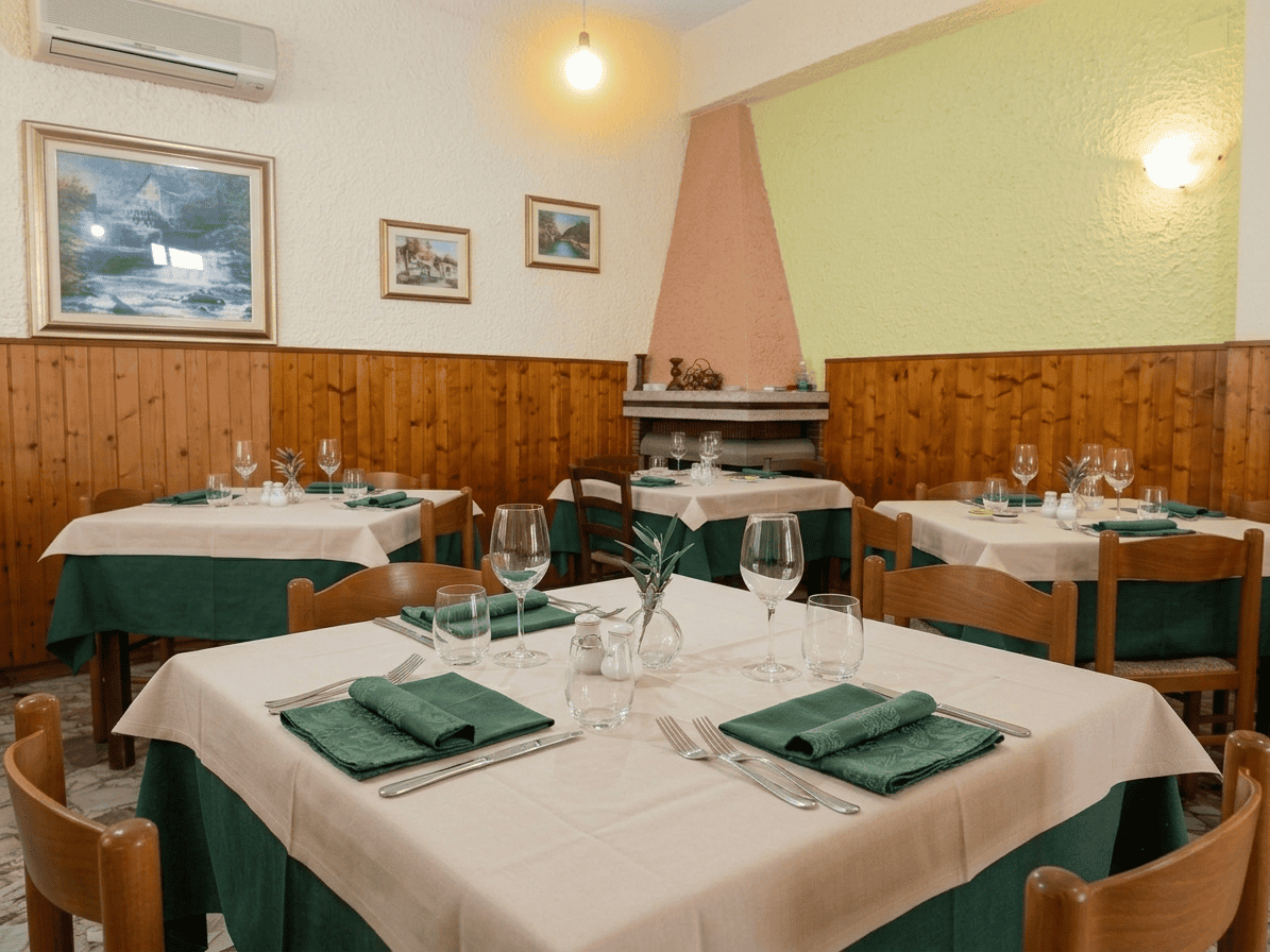 Interno di un ristorante con tavoli apparecchiati, decorazioni e camino, ambiente accogliente e ben illuminato.
