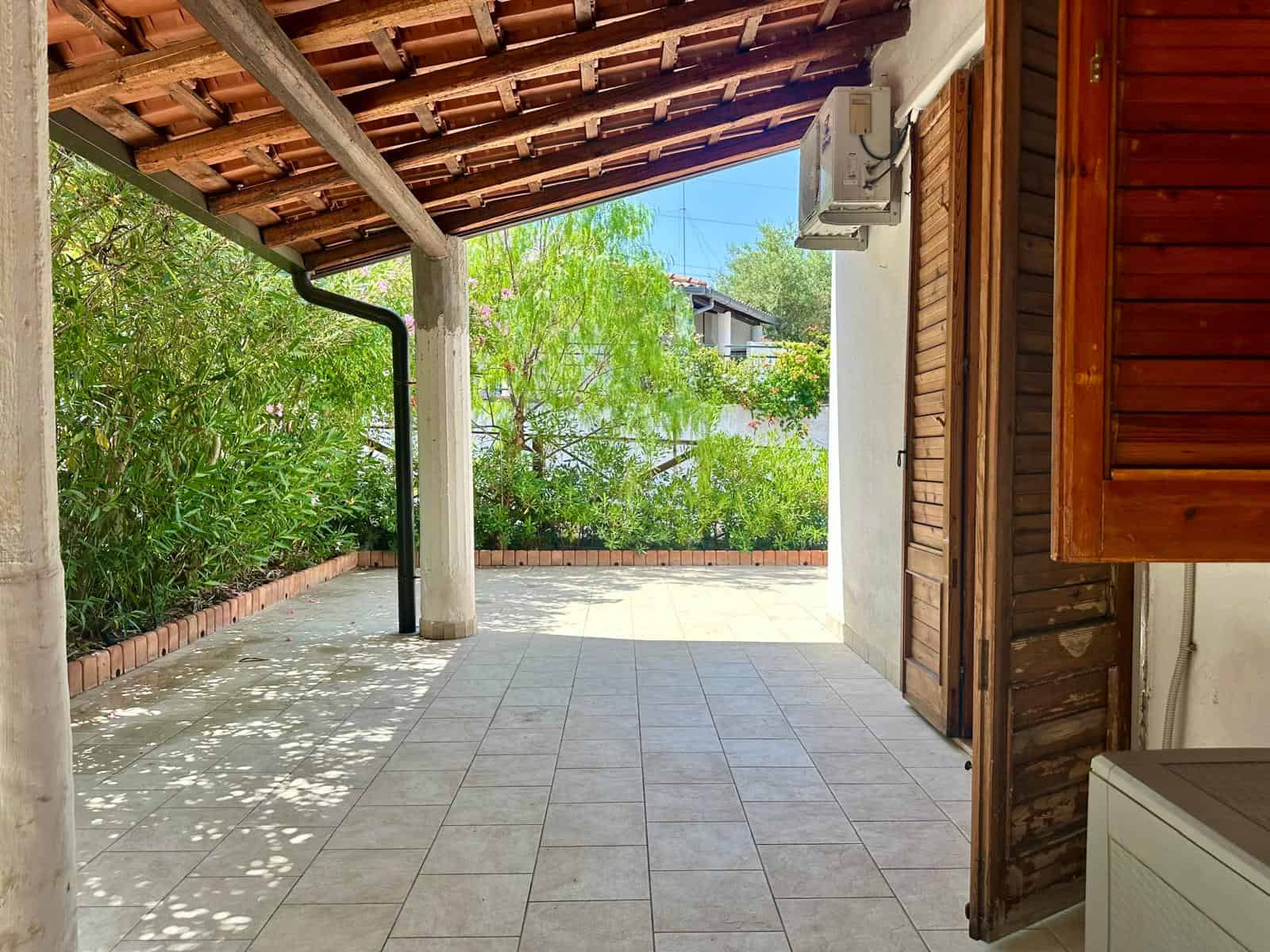 1 Terrazza esterna con tetto in legno, piante verdi e vista sul cielo azzurro, ideale per relax e convivialità.