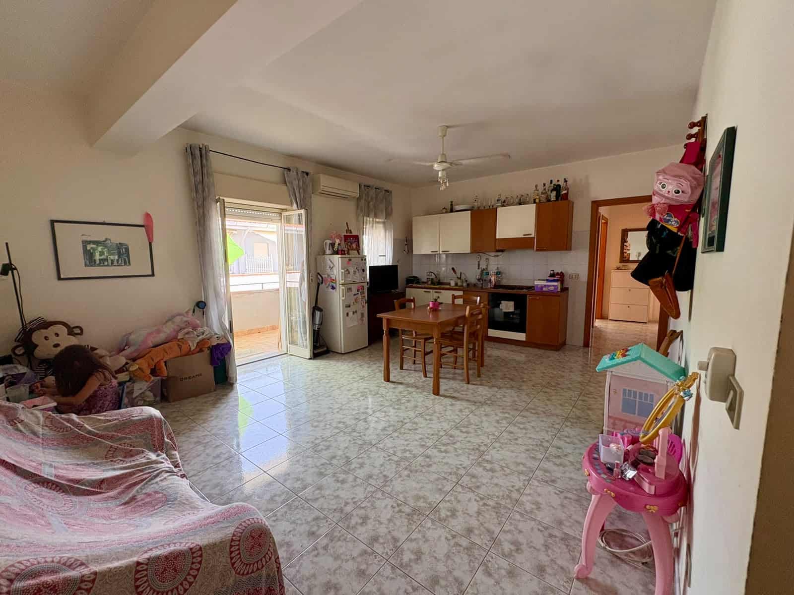 Interno di un appartamento con cucina e zona soggiorno, arredato con mobili colorati e decorazioni.