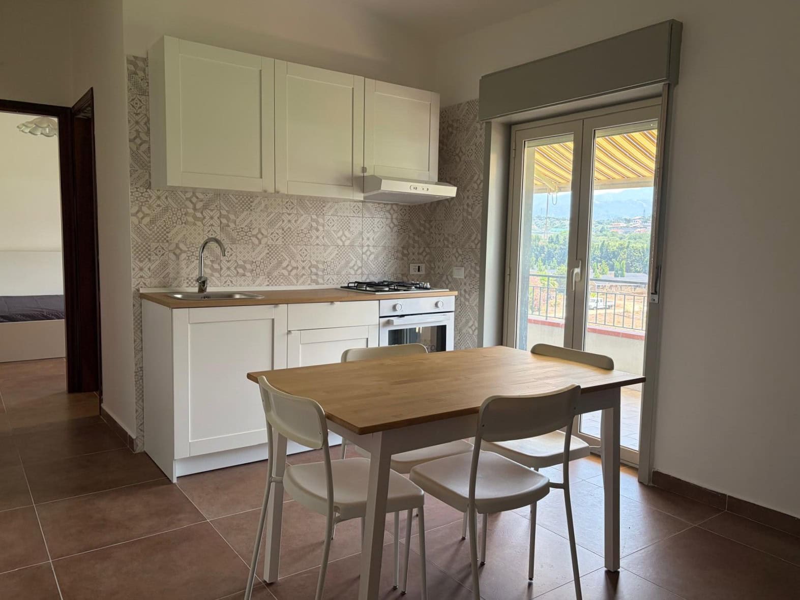 Cucina moderna in appartamento in affitto a Falcone, con tavolo e sedie, balcone con vista panoramica.