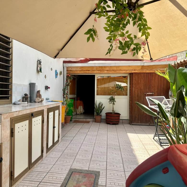 Spazio esterno con area barbecue, piante e ombrellone, ideale per relax e socializzazione all'aperto.