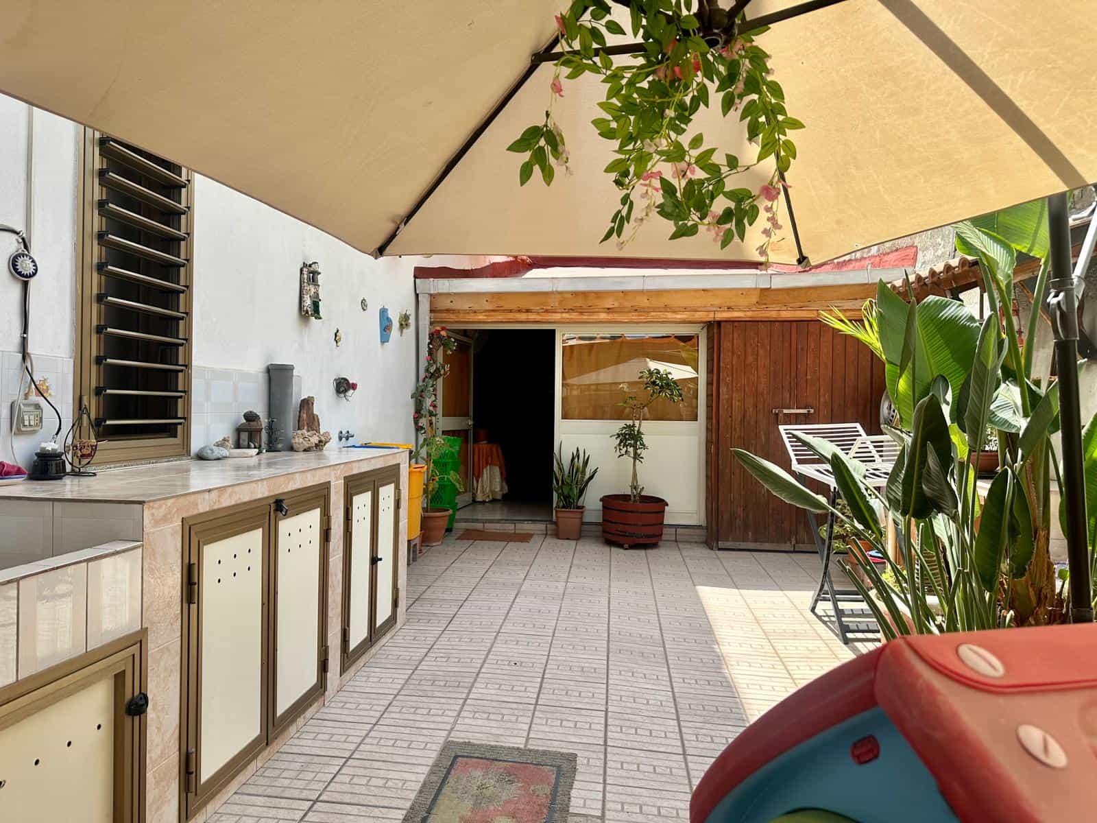 Spazio esterno con area barbecue, piante e ombrellone, ideale per relax e socializzazione all'aperto.