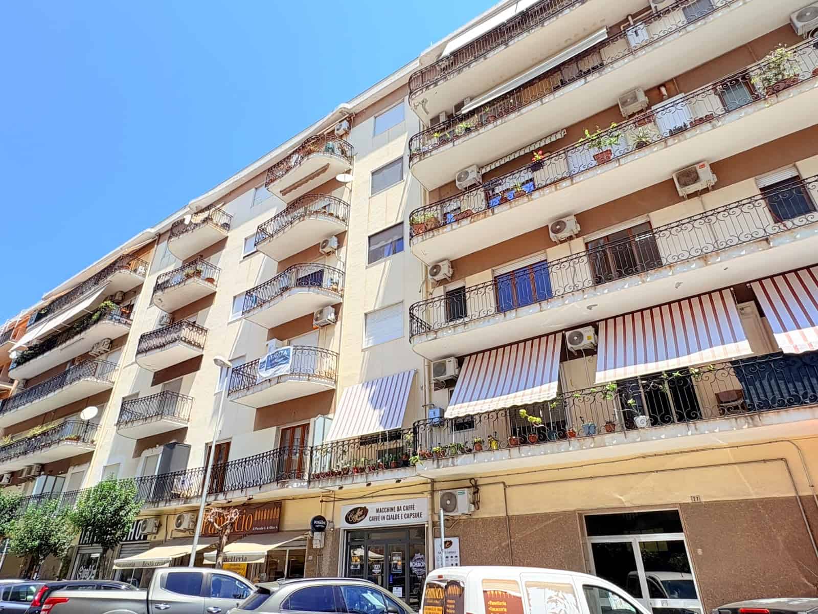 Facciata di un edificio residenziale con balconi e negozi al piano terra a Milazzo, ME.