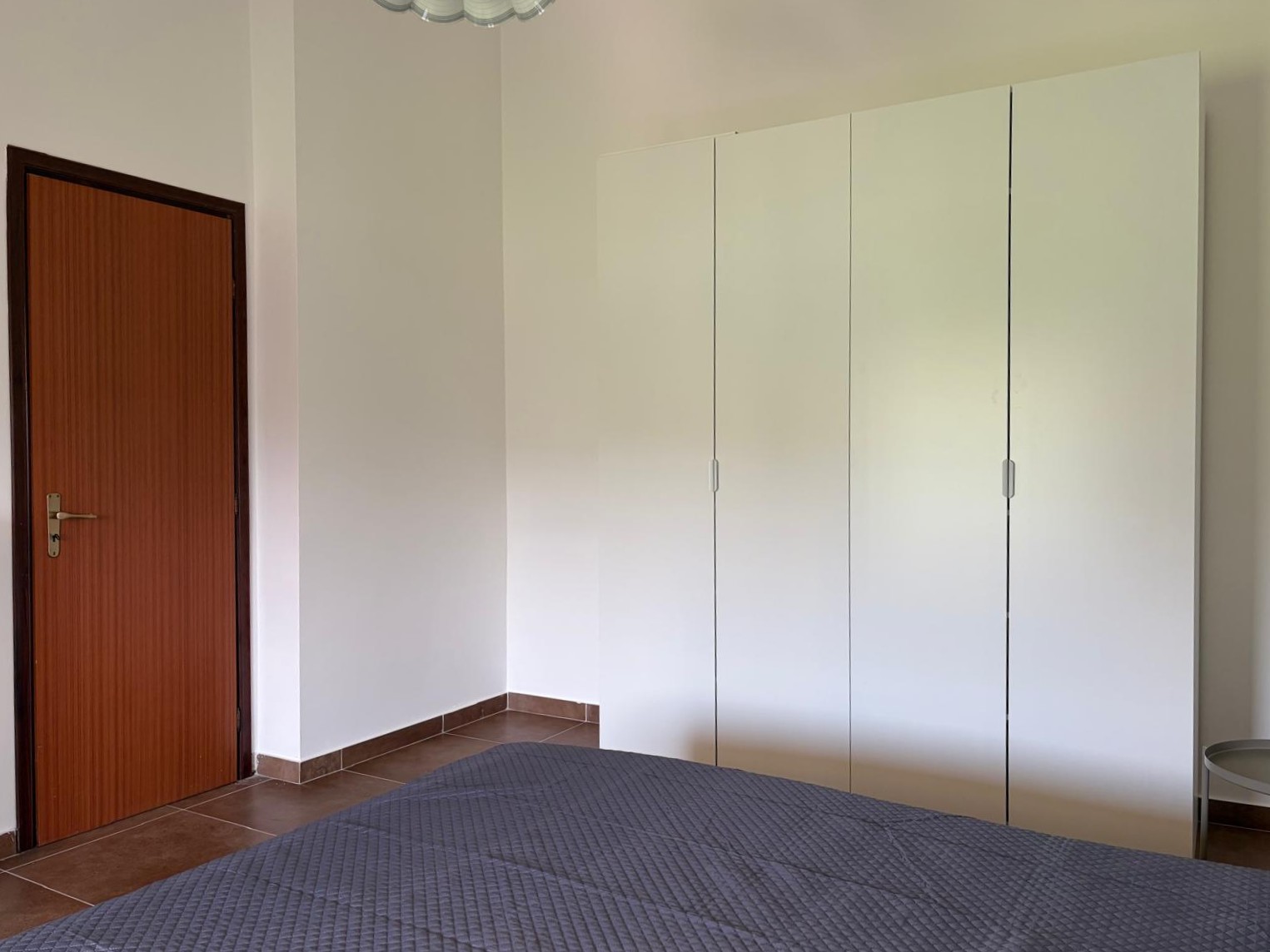 Camera da letto moderna con armadio bianco e letto con copriletto grigio, in appartamento in Via Nazionale 243, Falcone, Me.