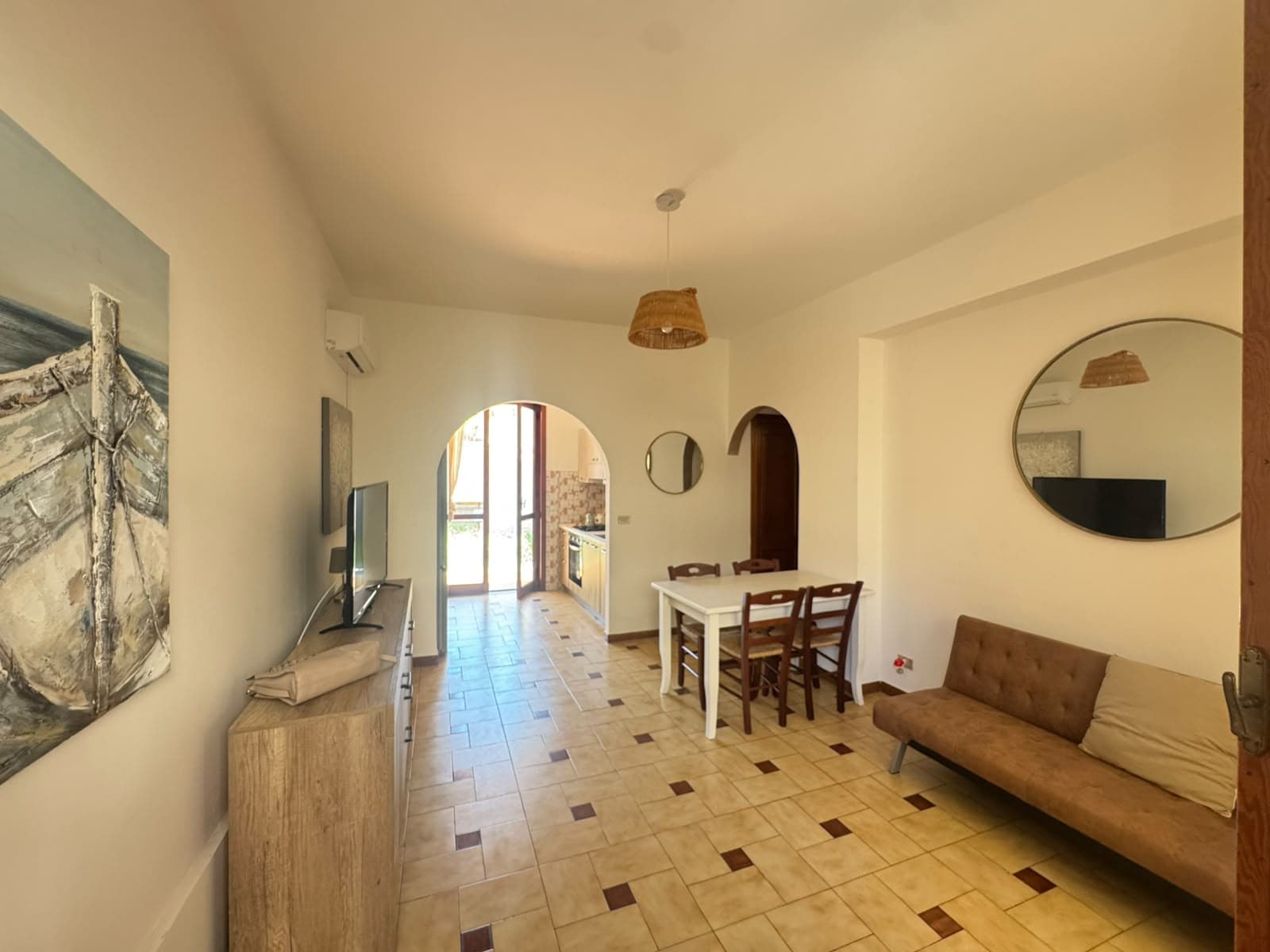 Interni di un soggiorno luminoso con divano, tavolo e TV, in una villa in vendita a Milazzo, Sicilia.