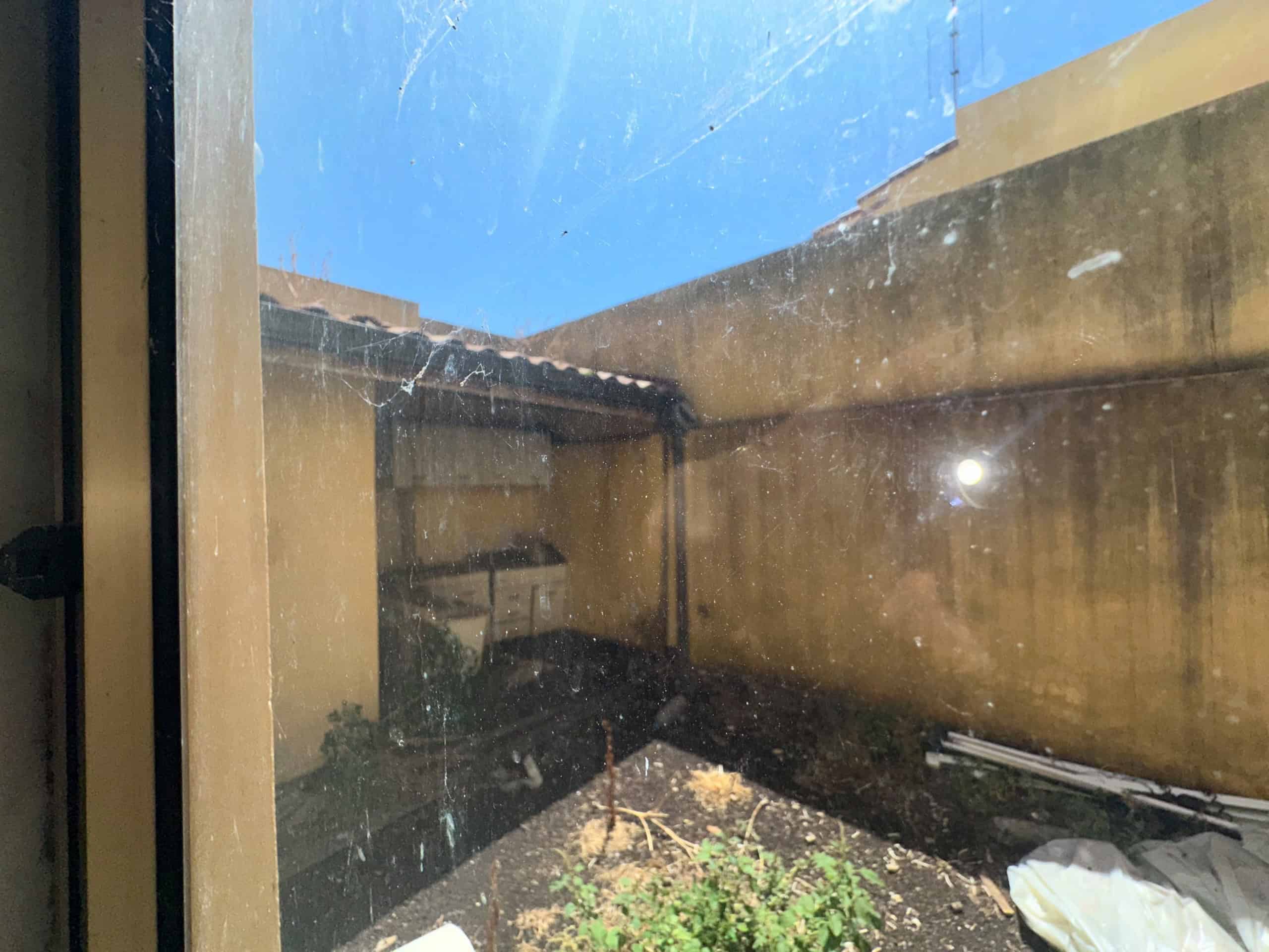 Vista di un cortile esterno di una casa indipendente a Milazzo, con pareti beige e cielo azzurro.
