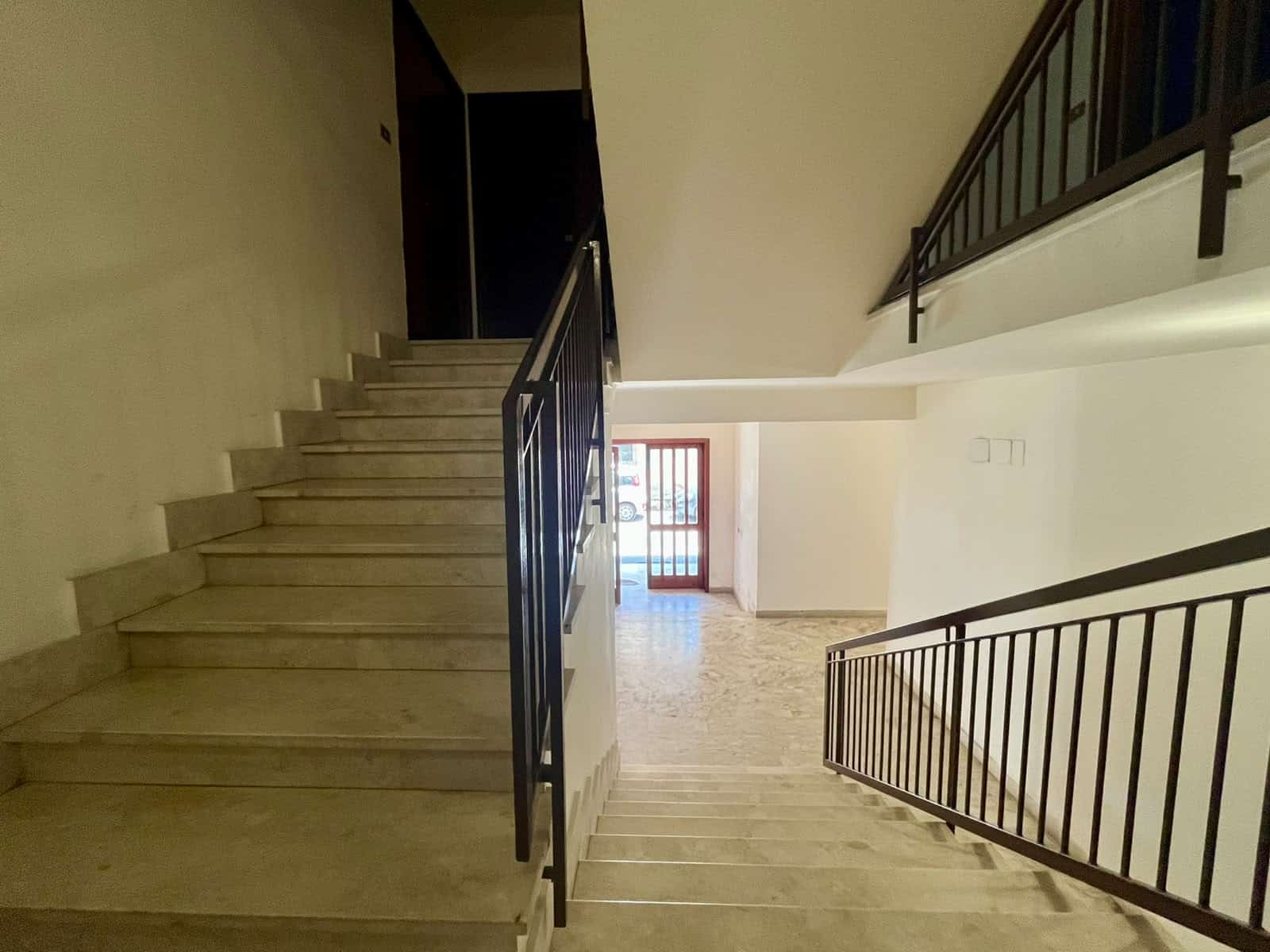 Interno di una scala in un appartamento in vendita a Oliveri, Me, con ringhiera in metallo e pareti bianche.