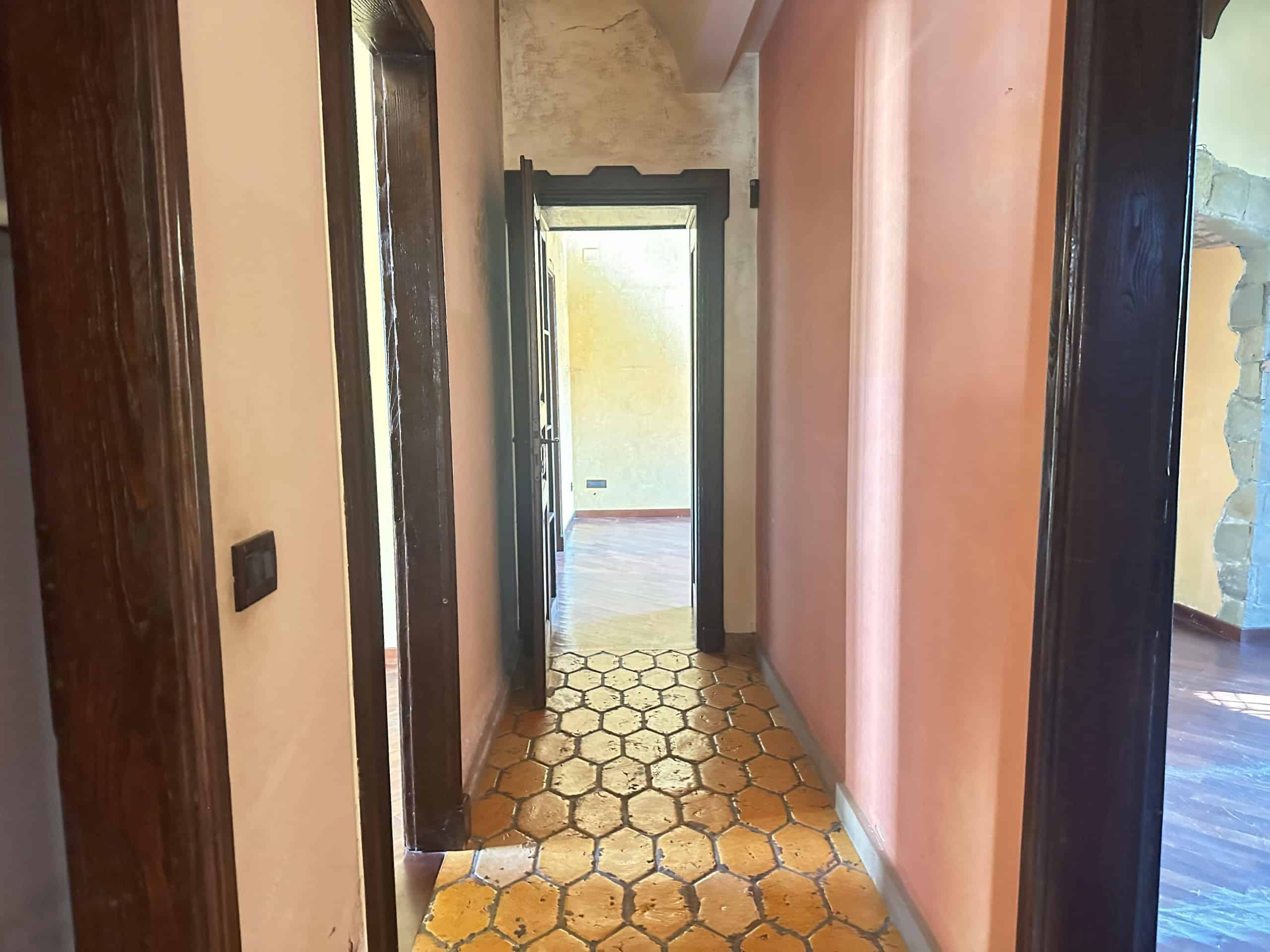 Ingresso di una villa in vendita a Milazzo, con pareti color pesca e pavimento in piastrelle esagonali.
