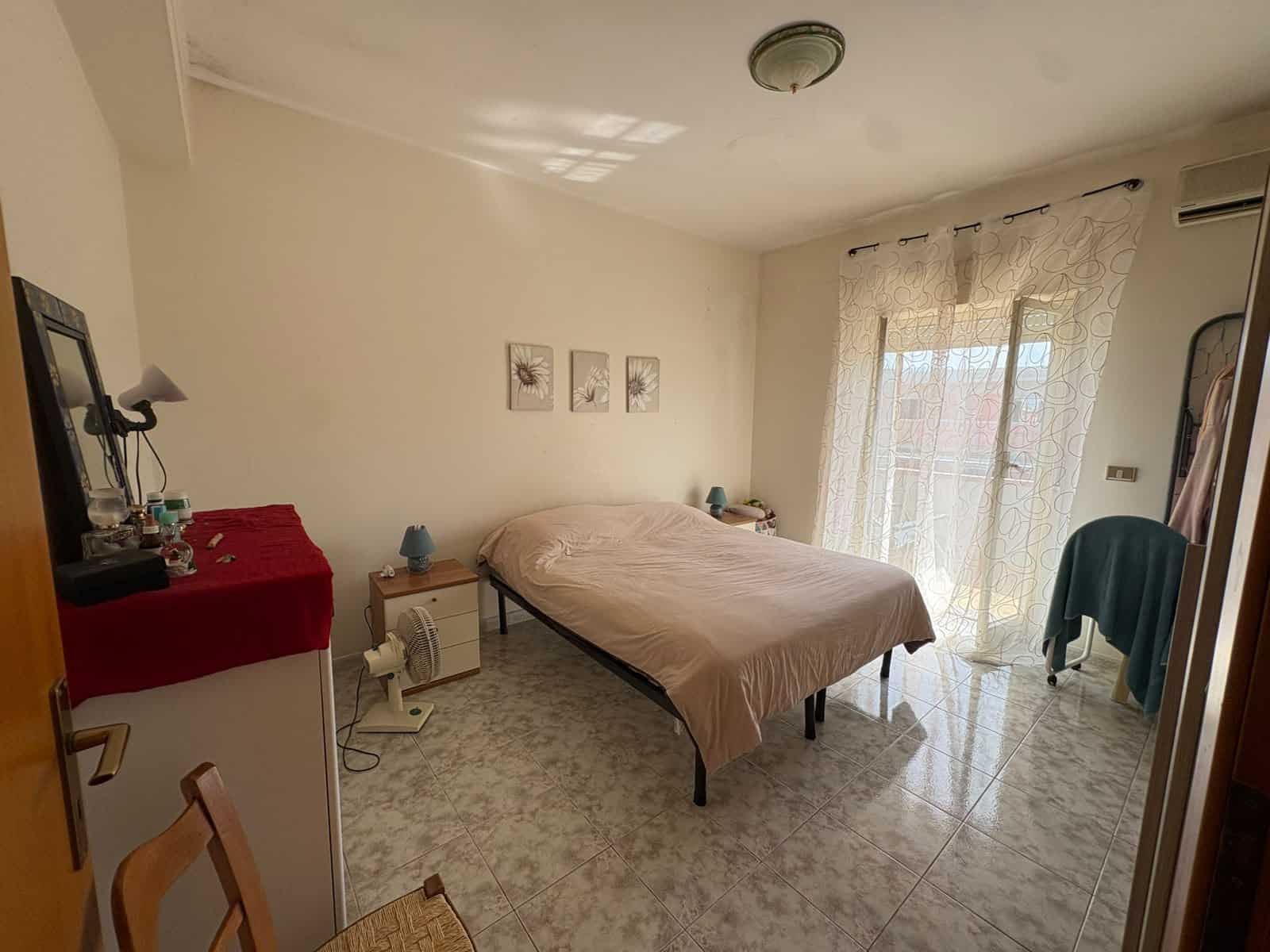 Camera da letto luminosa con accesso a terrazzo, arredamento semplice e tende leggere, in appartamento in vendita a Tonnarella.