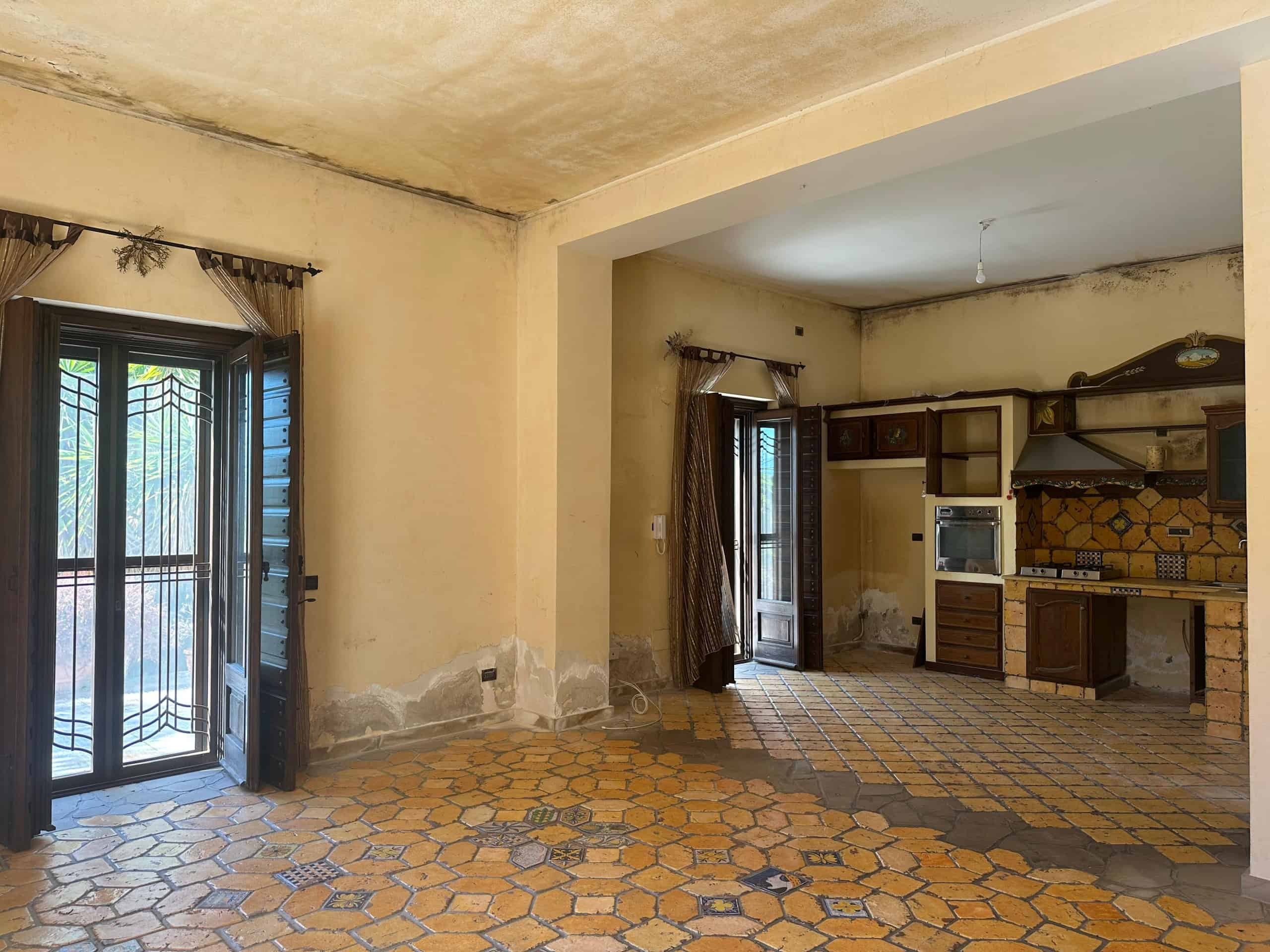 Interno di una villa in vendita a Milazzo con pareti usurate e cucina rustica.