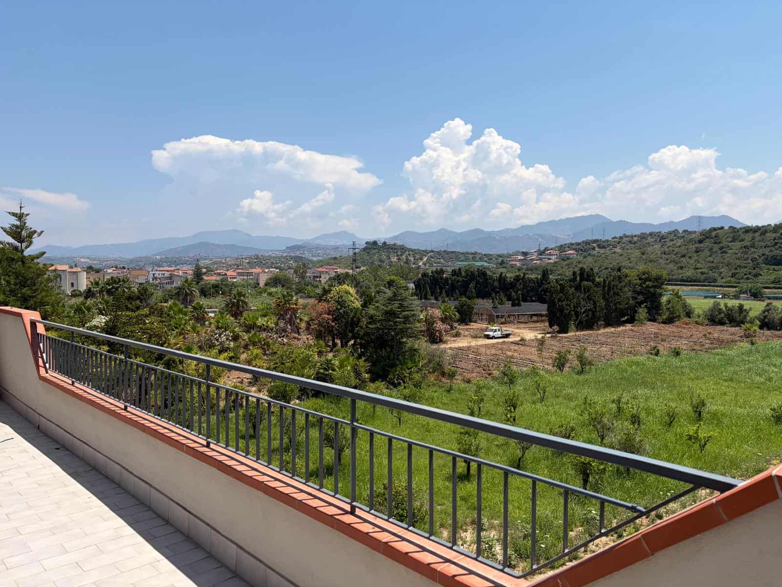 Vista panoramica sulla campagna e le montagne dal balcone di un appartamento in affitto a Falcone, Messina.