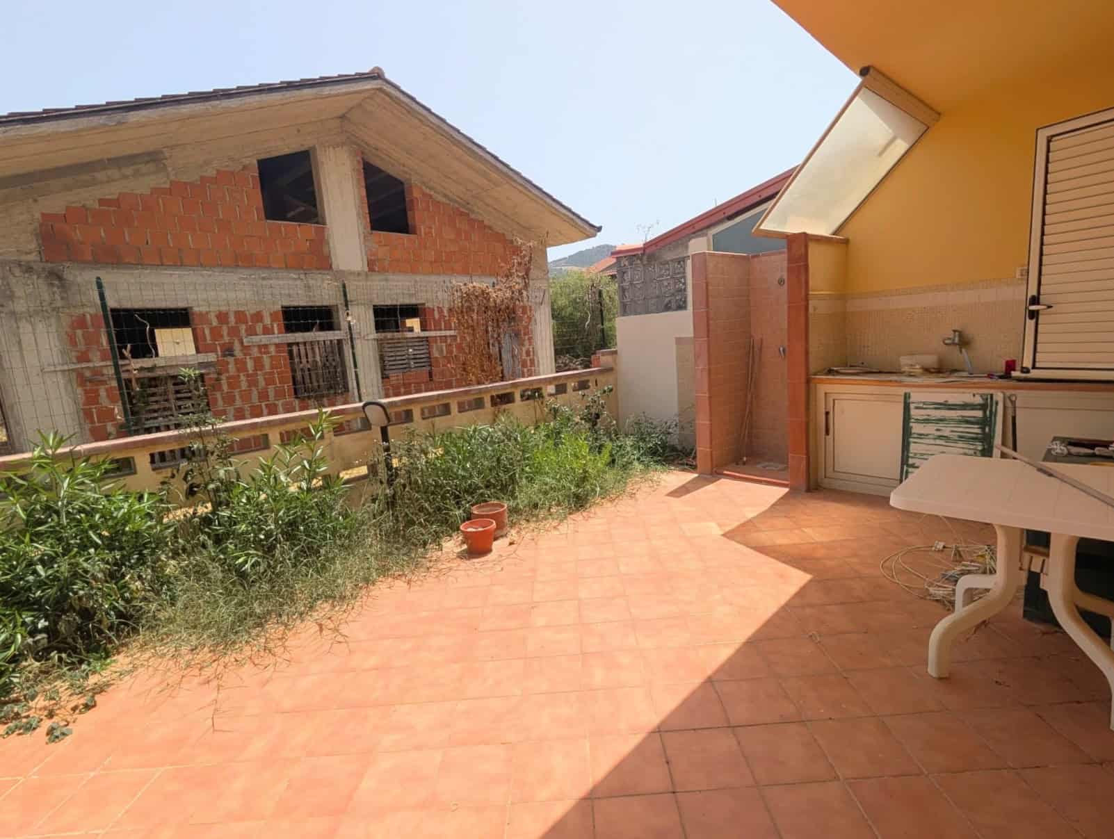Terrazza soleggiata con vista su case in costruzione e giardino con piante verdi, ideale per Villetta a schiera.
