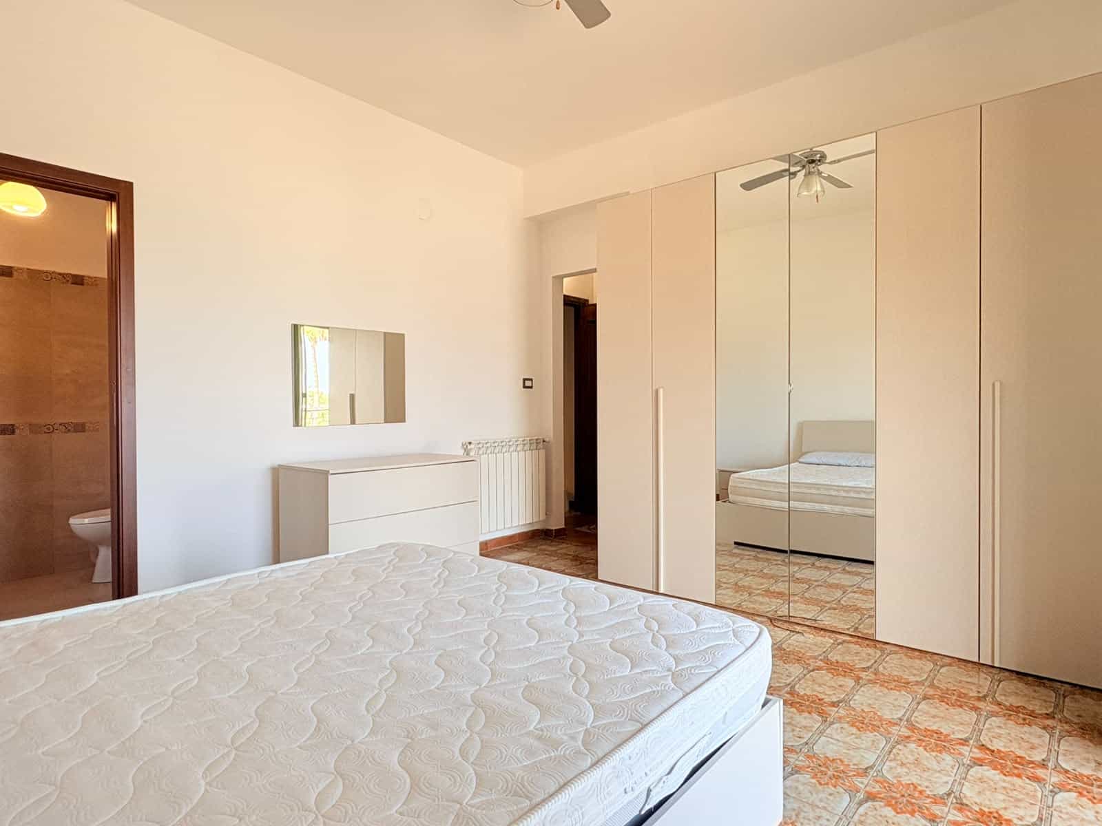Camera che mostra una camera da letto luminosa con armadio a specchio e letto matrimoniale in un appartamento in affitto a Milazzo.