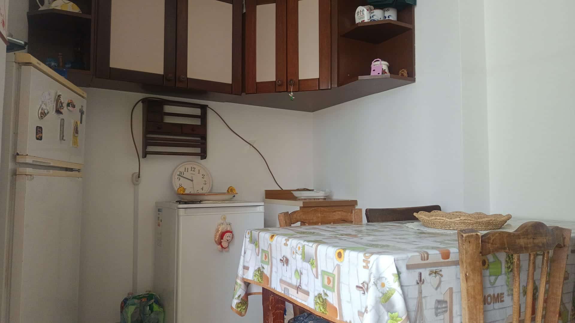 Interno di una cucina moderna con tavolo e sedie, armadietti in legno e elettrodomestici, in un appartamento in vendita a Rometta, ME.