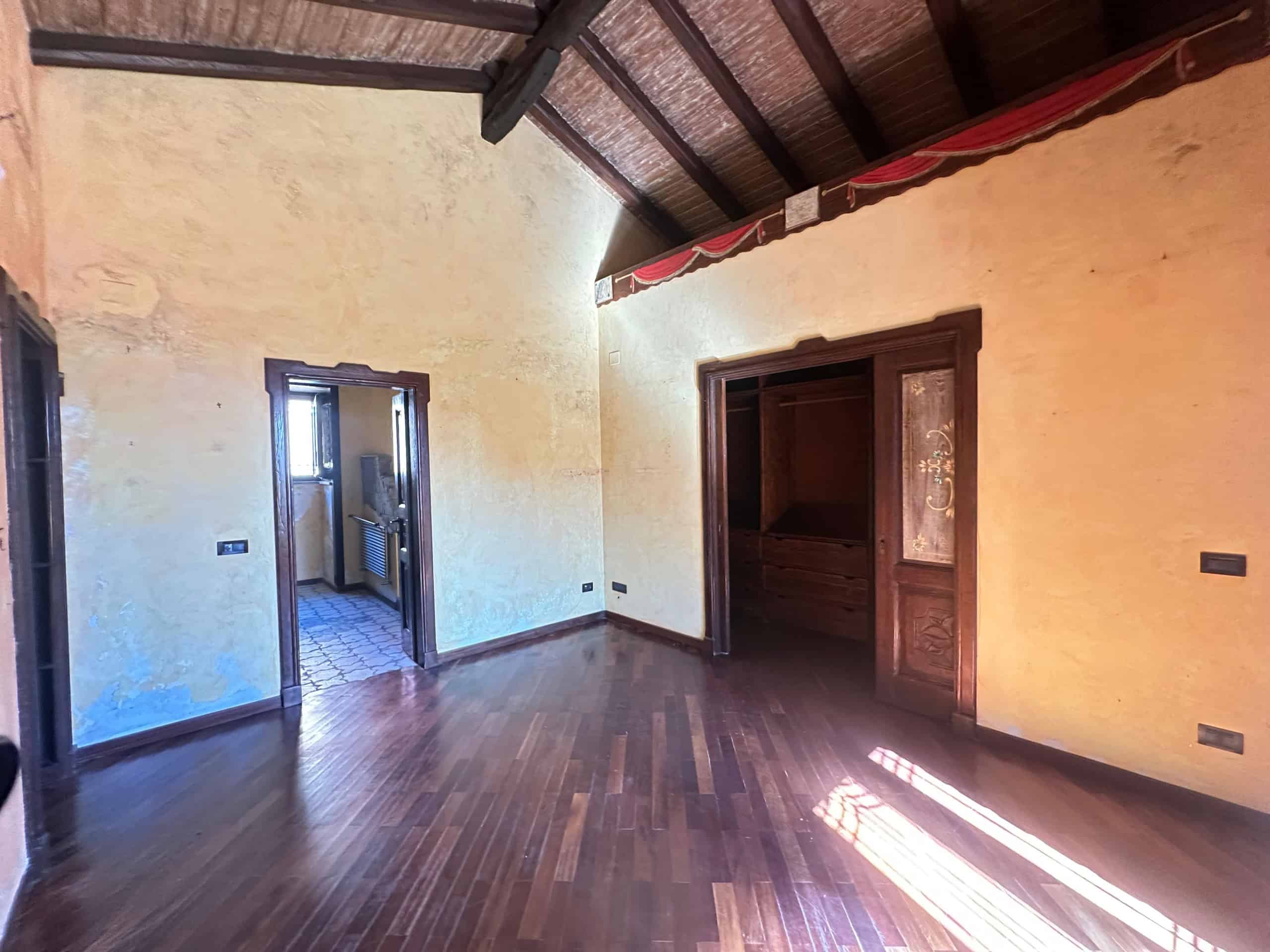 Interno di una villa in vendita a Milazzo, con pareti gialle, pavimento in legno e soffitto a volta in legno.
