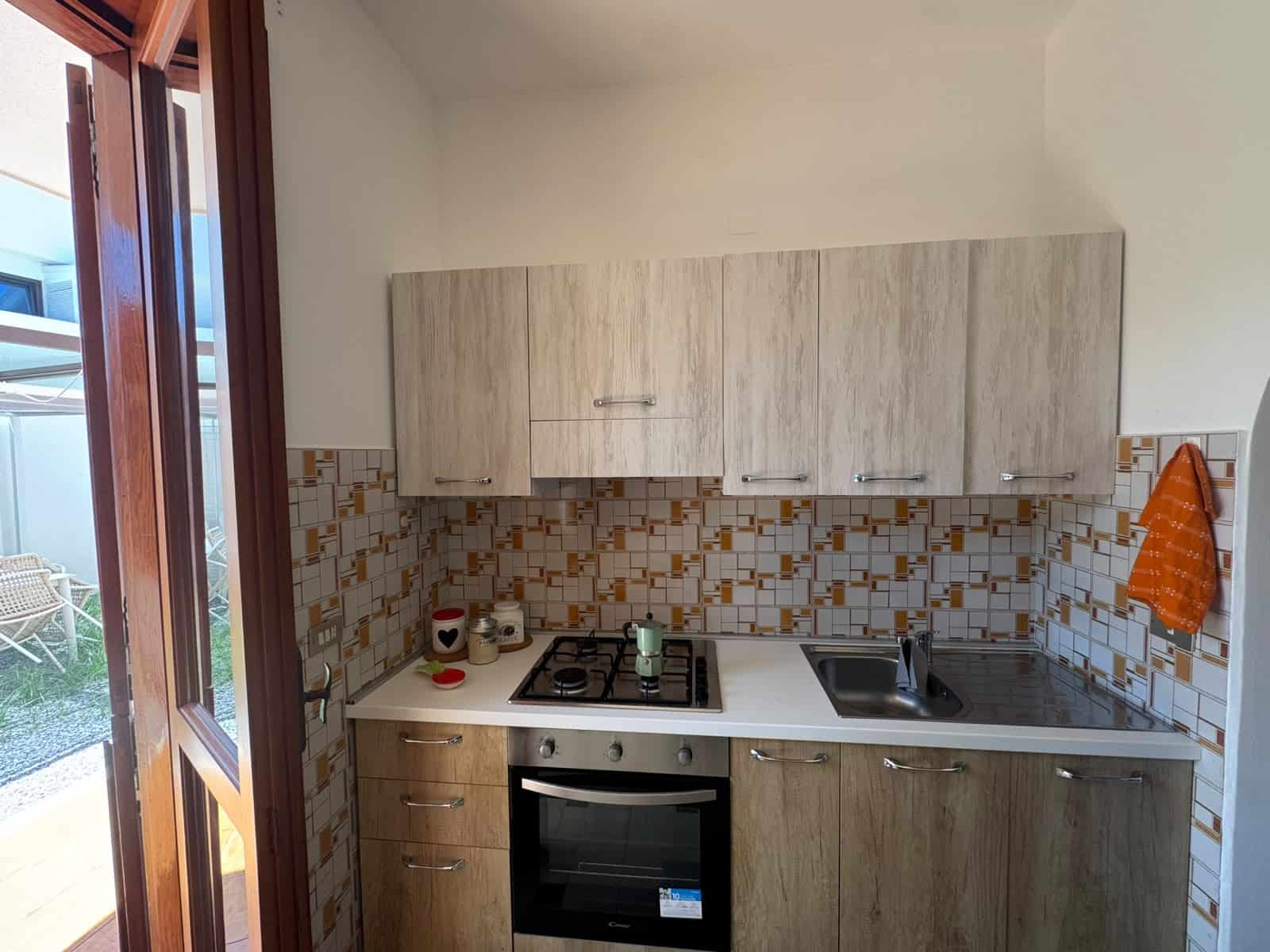 Cucina moderna in appartamento a Milazzo con mobili chiari e piano cottura a gas.