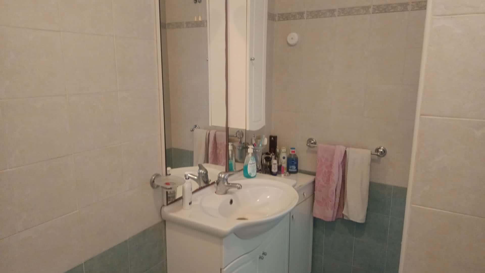 Bagno moderno con lavabo, specchio e asciugamani rosa in appartamento in vendita a Rometta, ME.