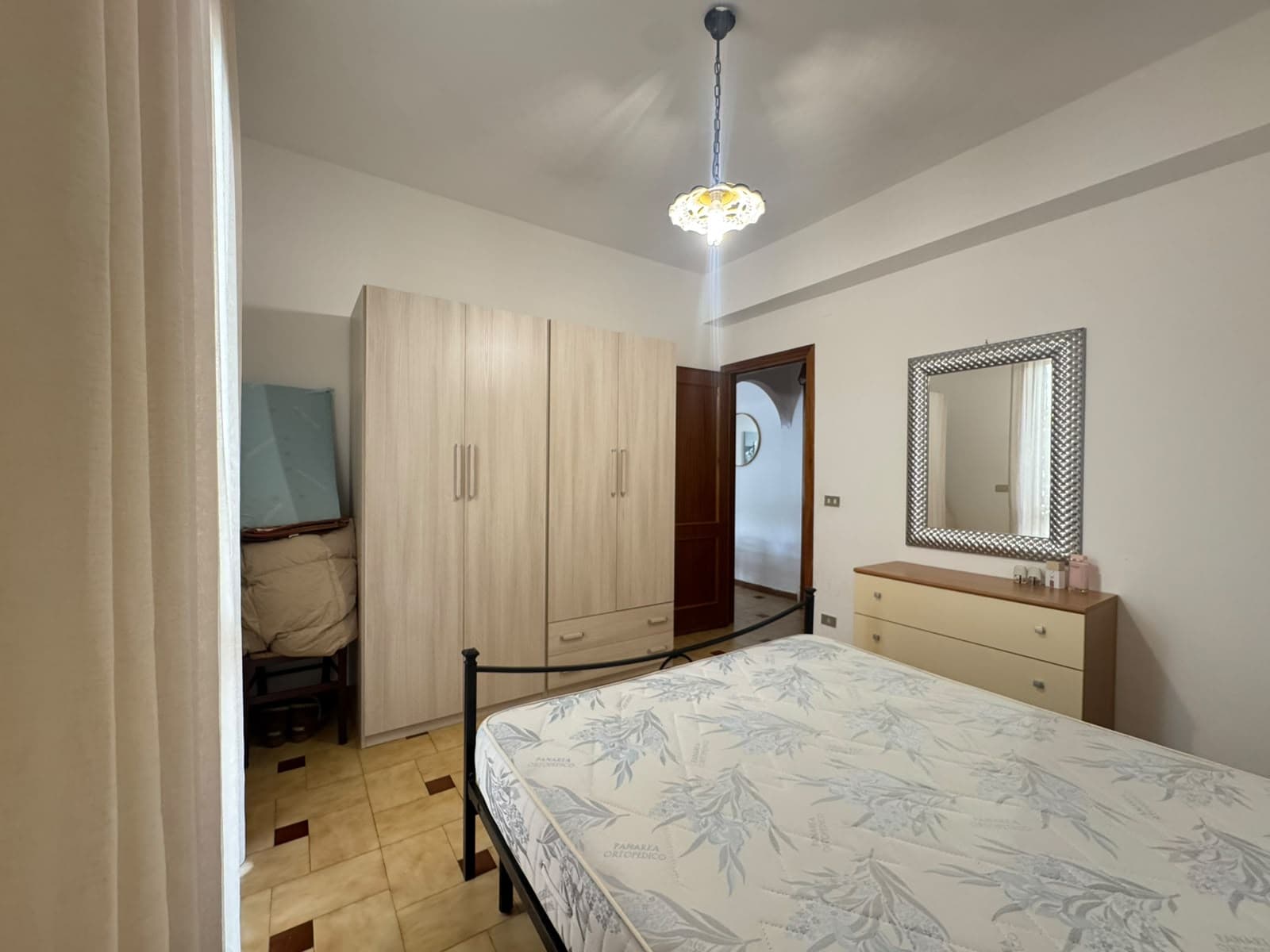 Camera che mostra una camera da letto con armadio, letto e specchio, in un appartamento in vendita a Milazzo.