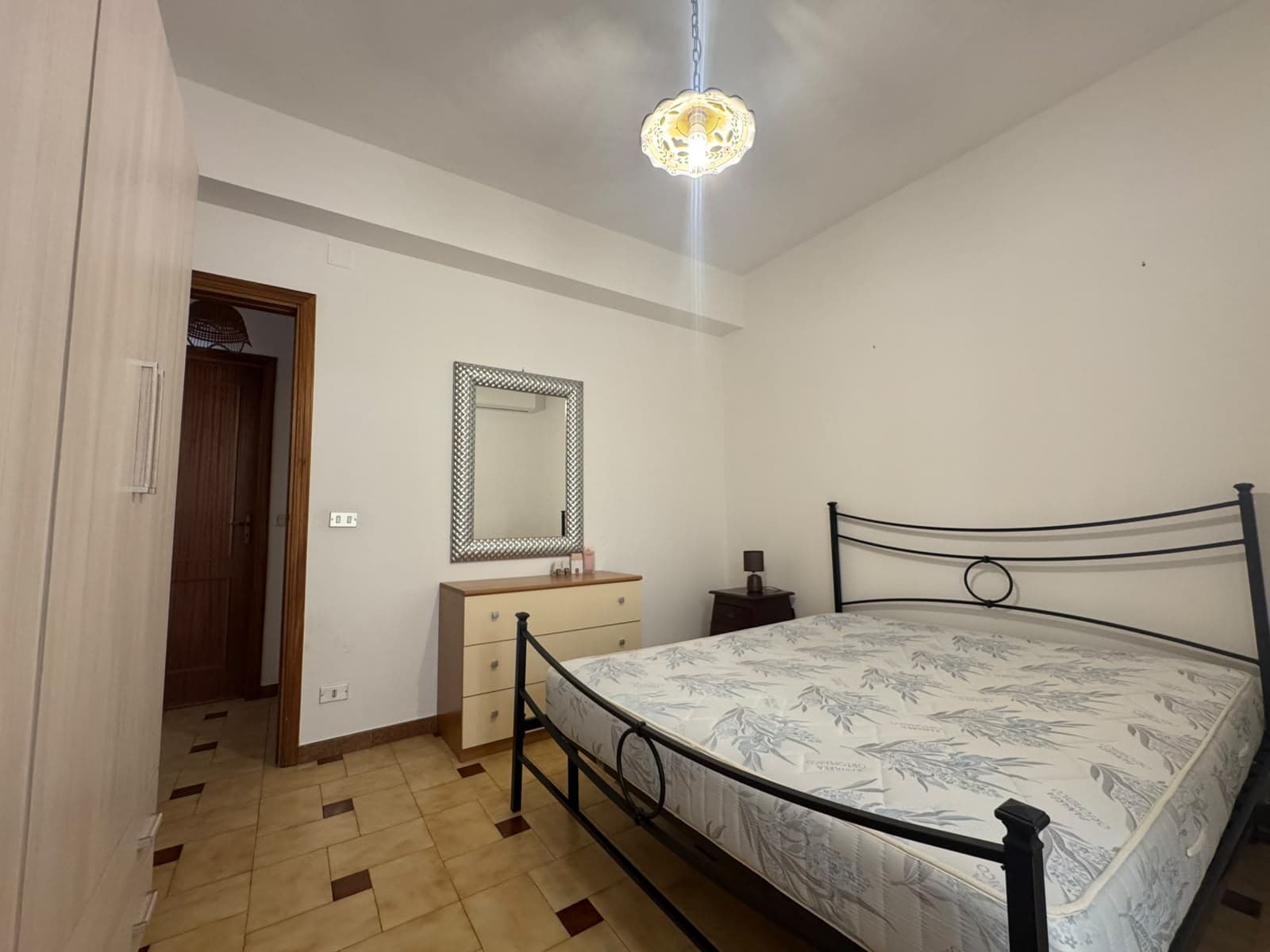 Camera da letto con letto matrimoniale, armadio e specchio, ambiente luminoso e accogliente.