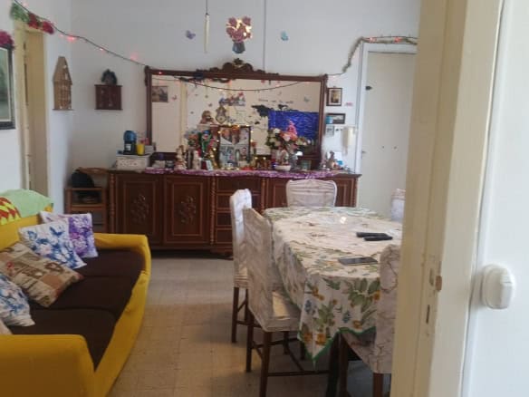 Interno soggiorno con divano giallo, tavolo da pranzo e decorazioni natalizie, in un appartamento in vendita a Rometta, ME.