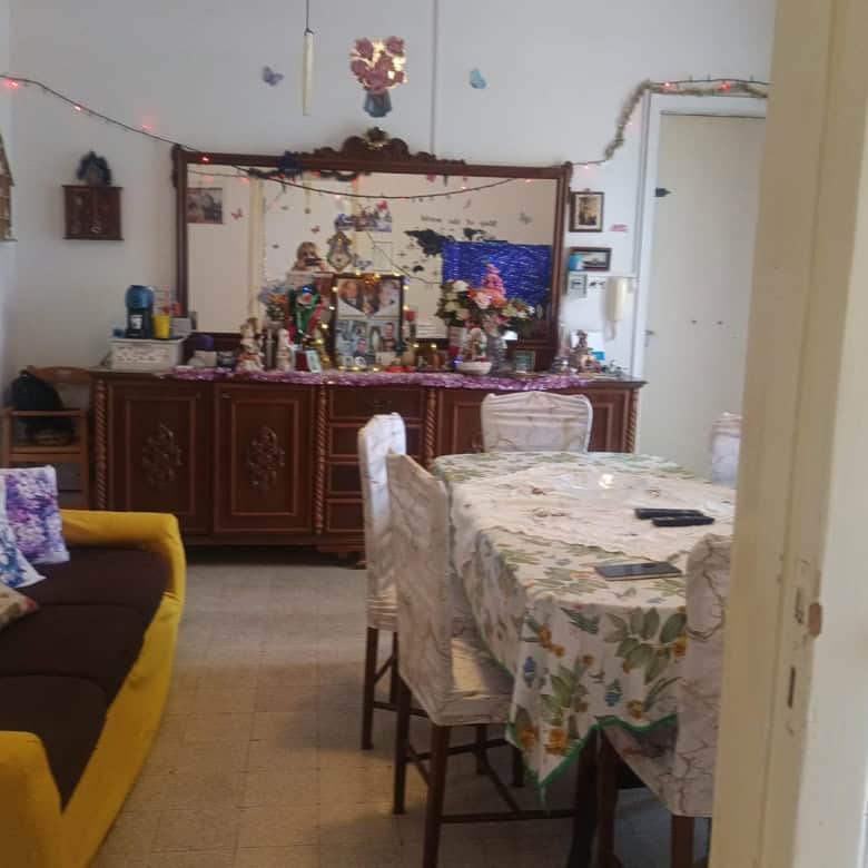 Interno soggiorno con divano giallo, tavolo da pranzo e decorazioni natalizie, in un appartamento in vendita a Rometta, ME.