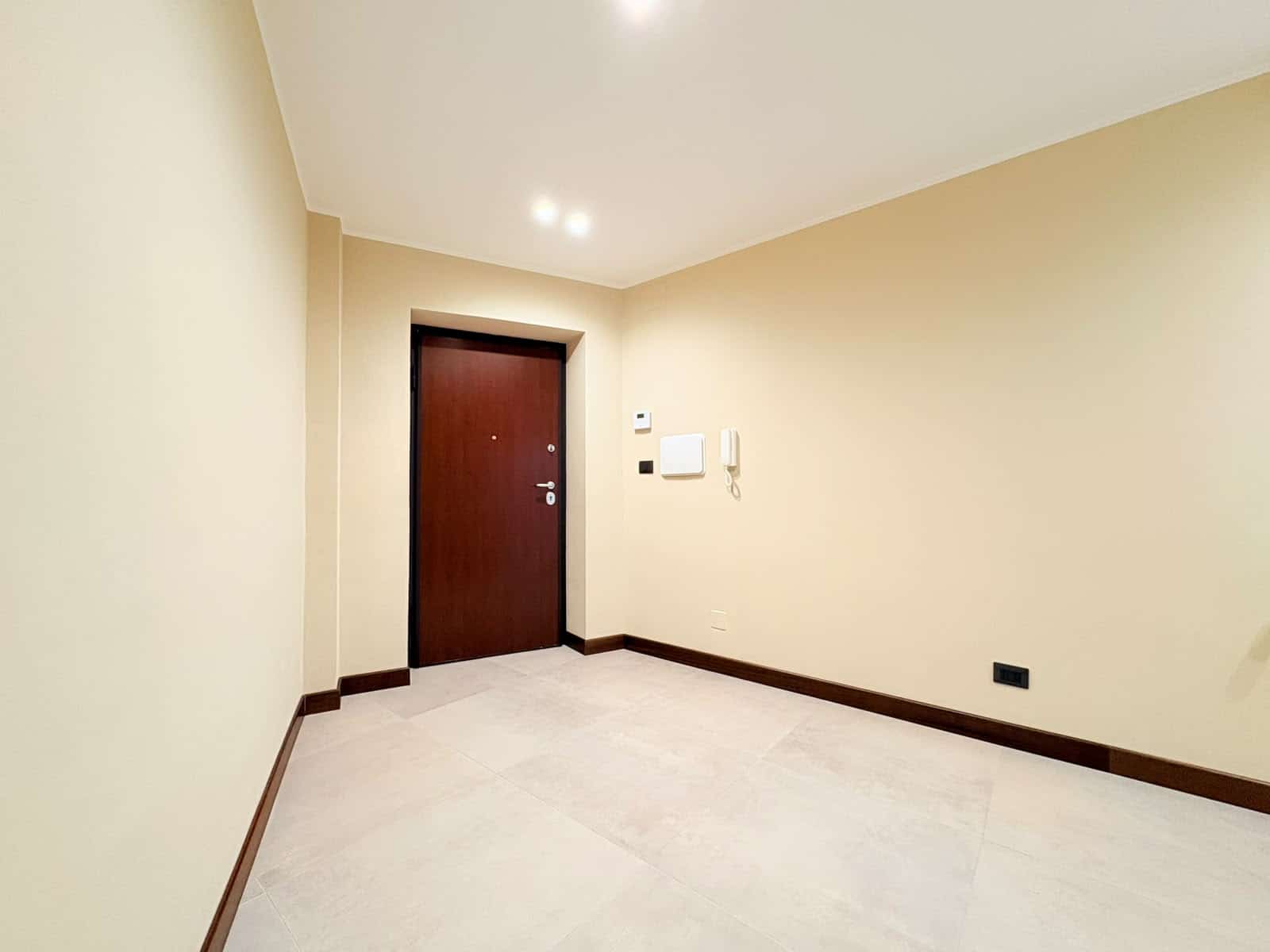 Ingresso di un appartamento in vendita in Via Colonnello F. Magistri 27, Milazzo, con porta in legno e pareti beige.
