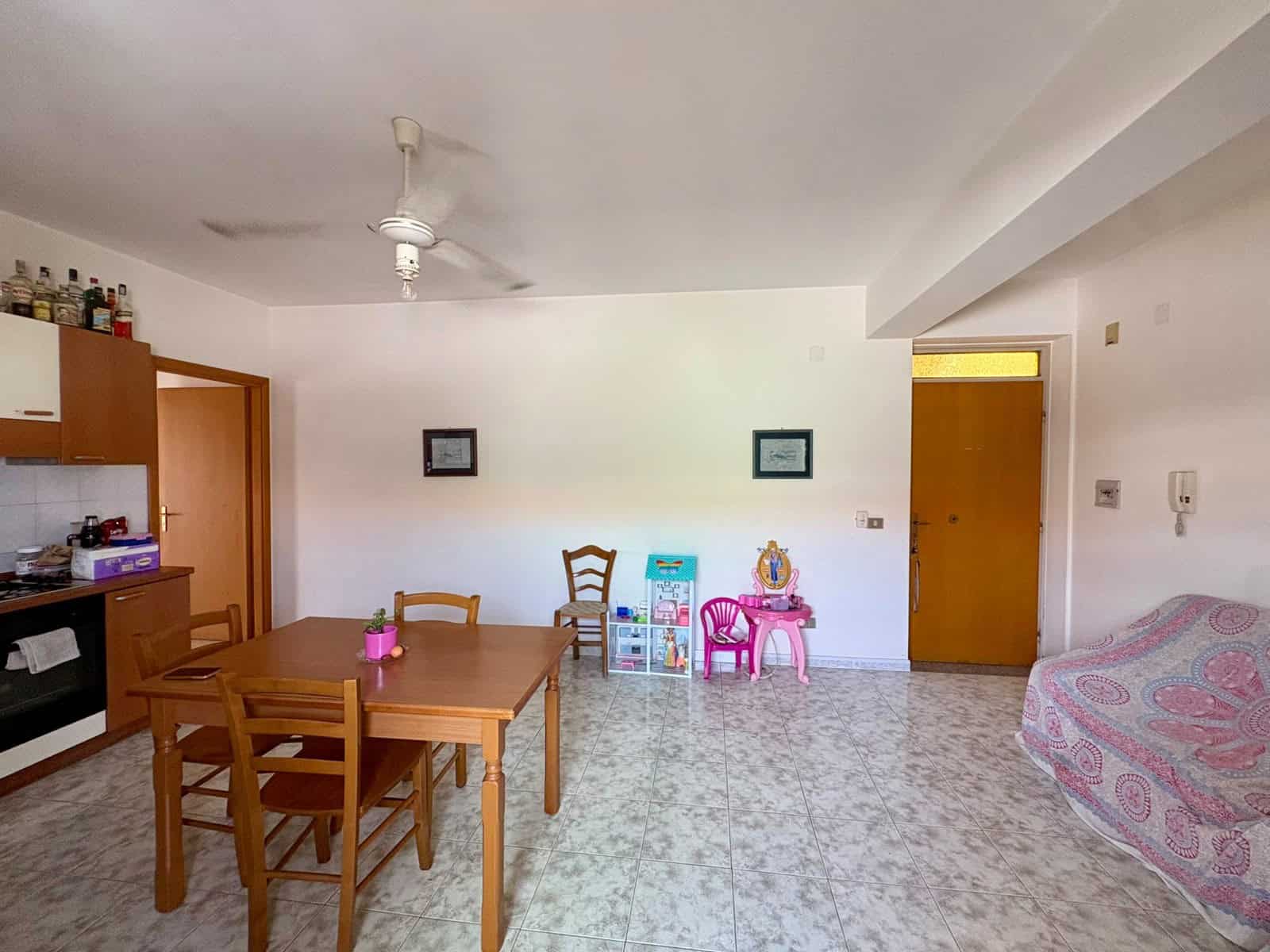 2 Interno di un appartamento con soggiorno, tavolo da pranzo, divano e accessori per bambini, in vendita a Tonnarella, Furnari, Messina.