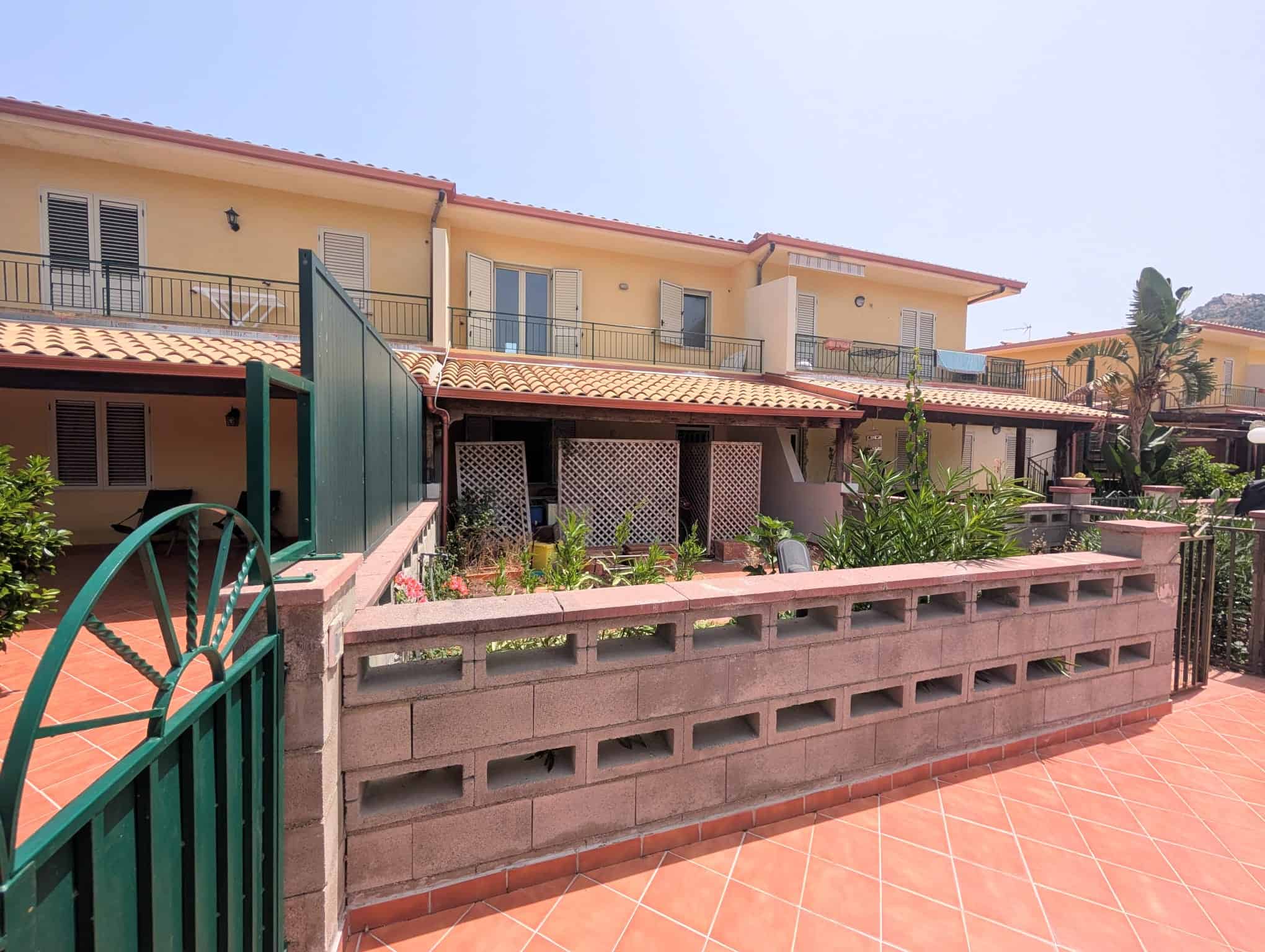 Villetta a schiera con giardino e terrazza, facciata gialla, in zona residenziale soleggiata.
