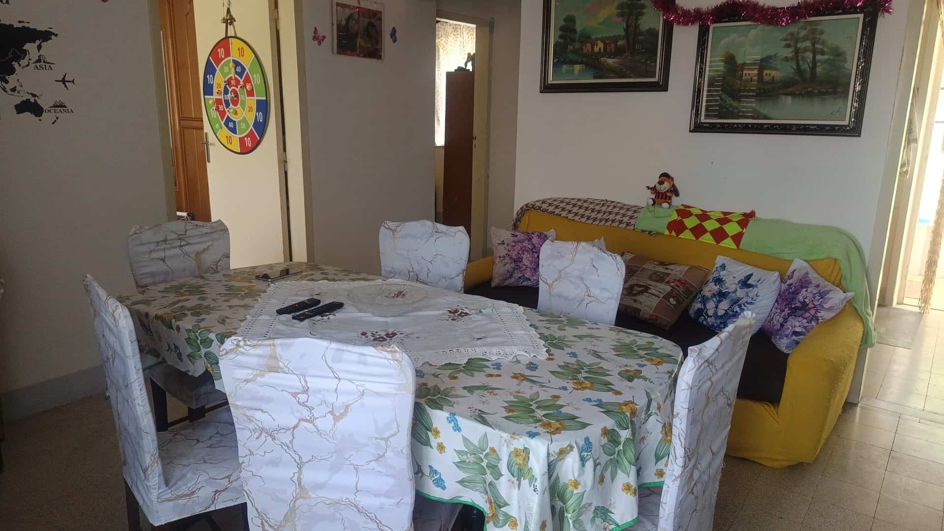 Interno soggiorno con tavolo da pranzo, divano e decorazioni natalizie, ambiente accogliente e luminoso.