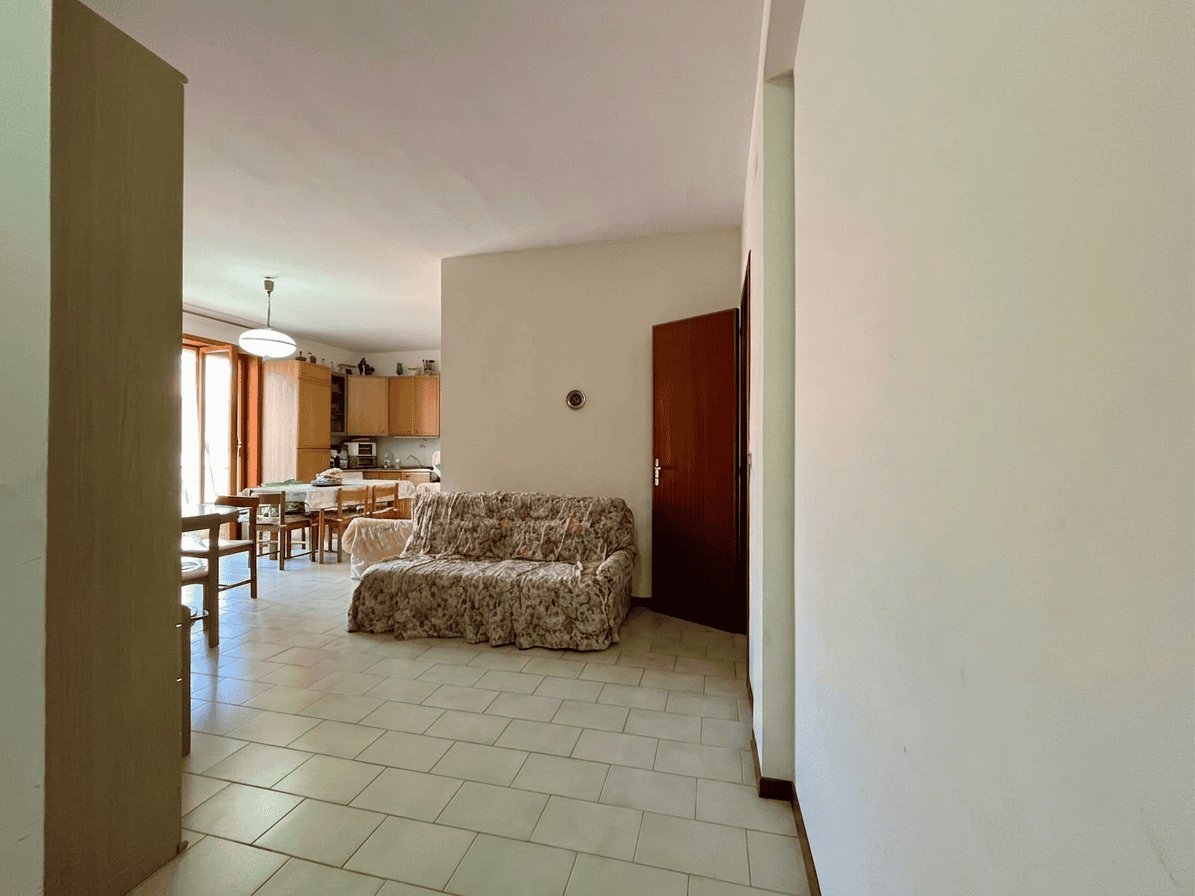 Interno di un appartamento in vendita a Oliveri, con soggiorno e zona pranzo, arredato con divano e mobili in legno, luminoso grazie alle finestre.