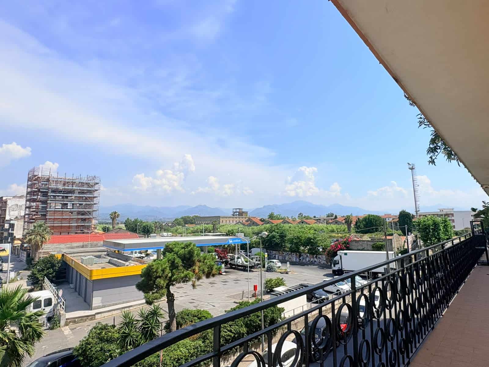 Vista panoramica di Milazzo con cielo azzurro e montagne sullo sfondo dalla terrazza di un appartamento.