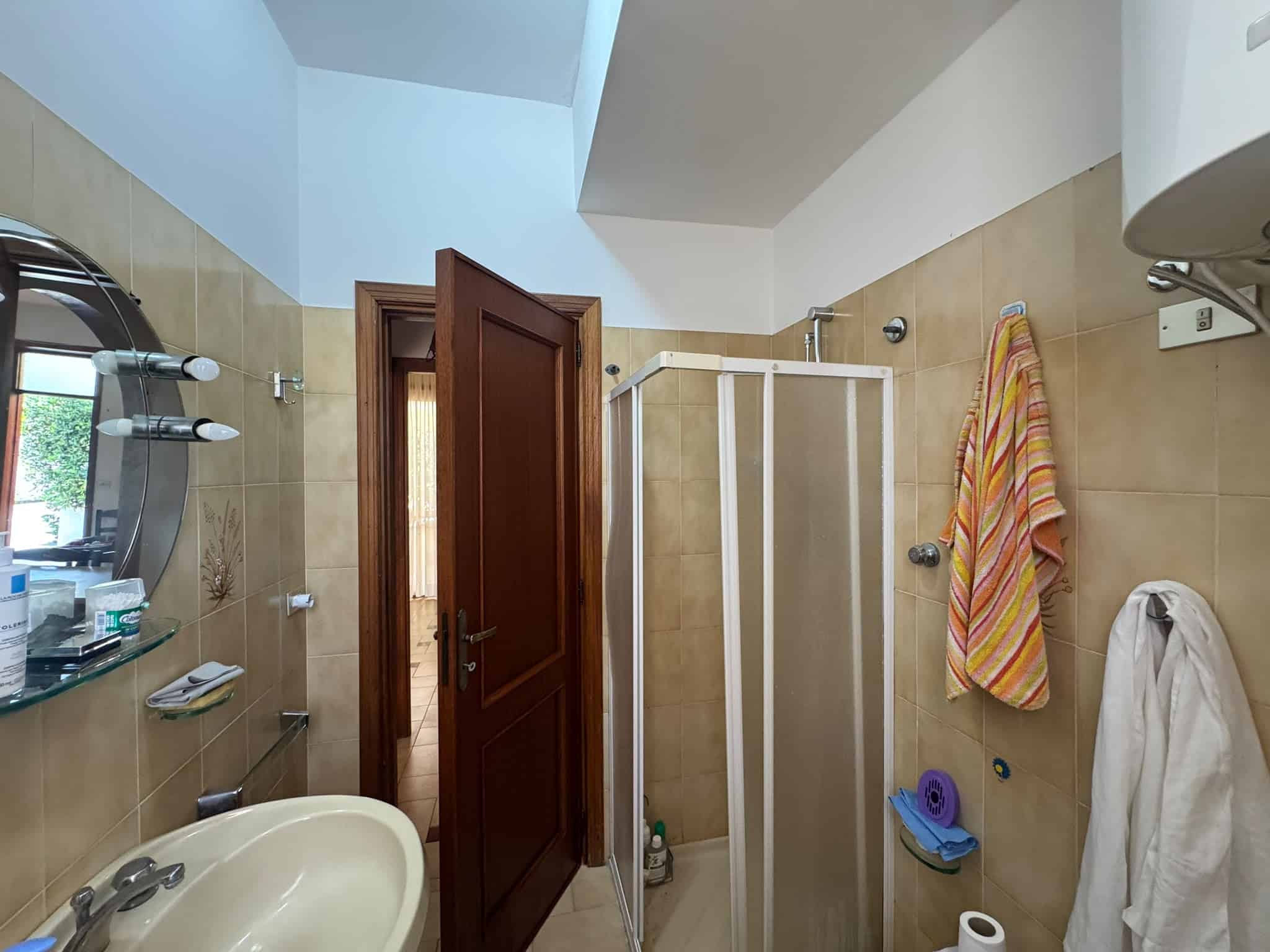 Bagno in villa in vendita a Milazzo con doccia, specchio e accessori.