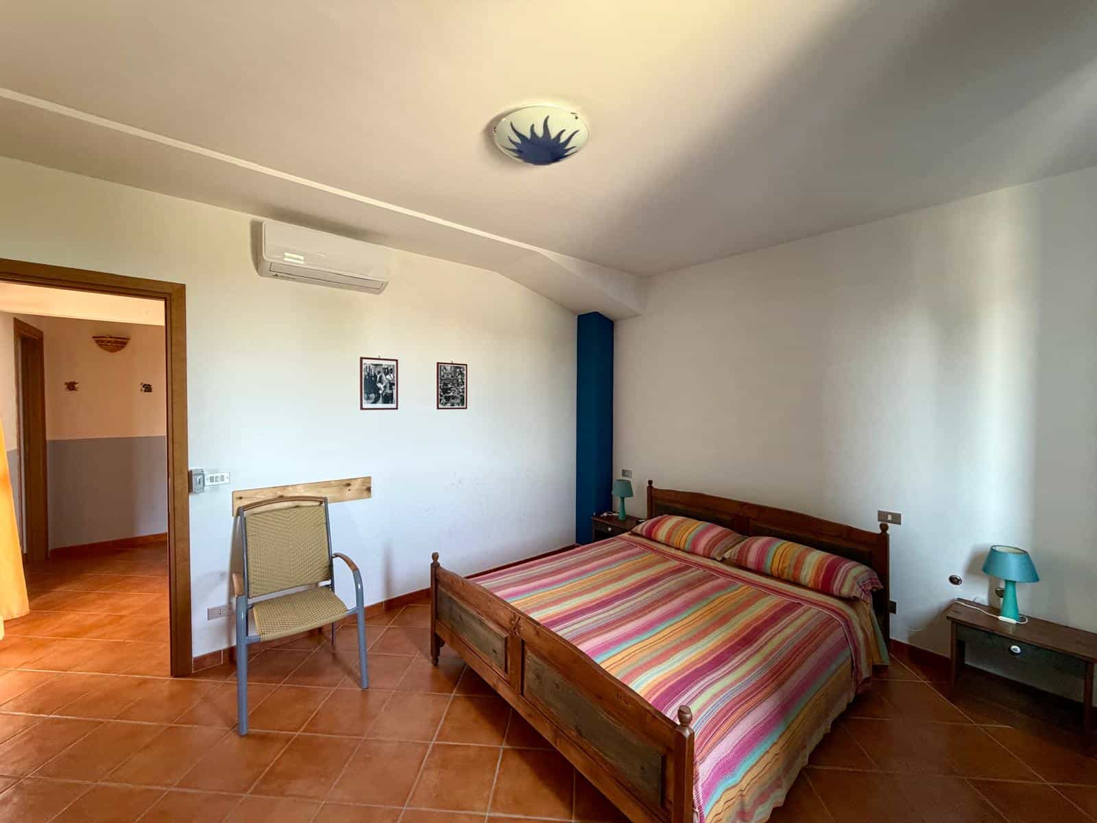 Camera da letto con letto matrimoniale, lampada da tavolo e aria condizionata, ambiente luminoso e accogliente.