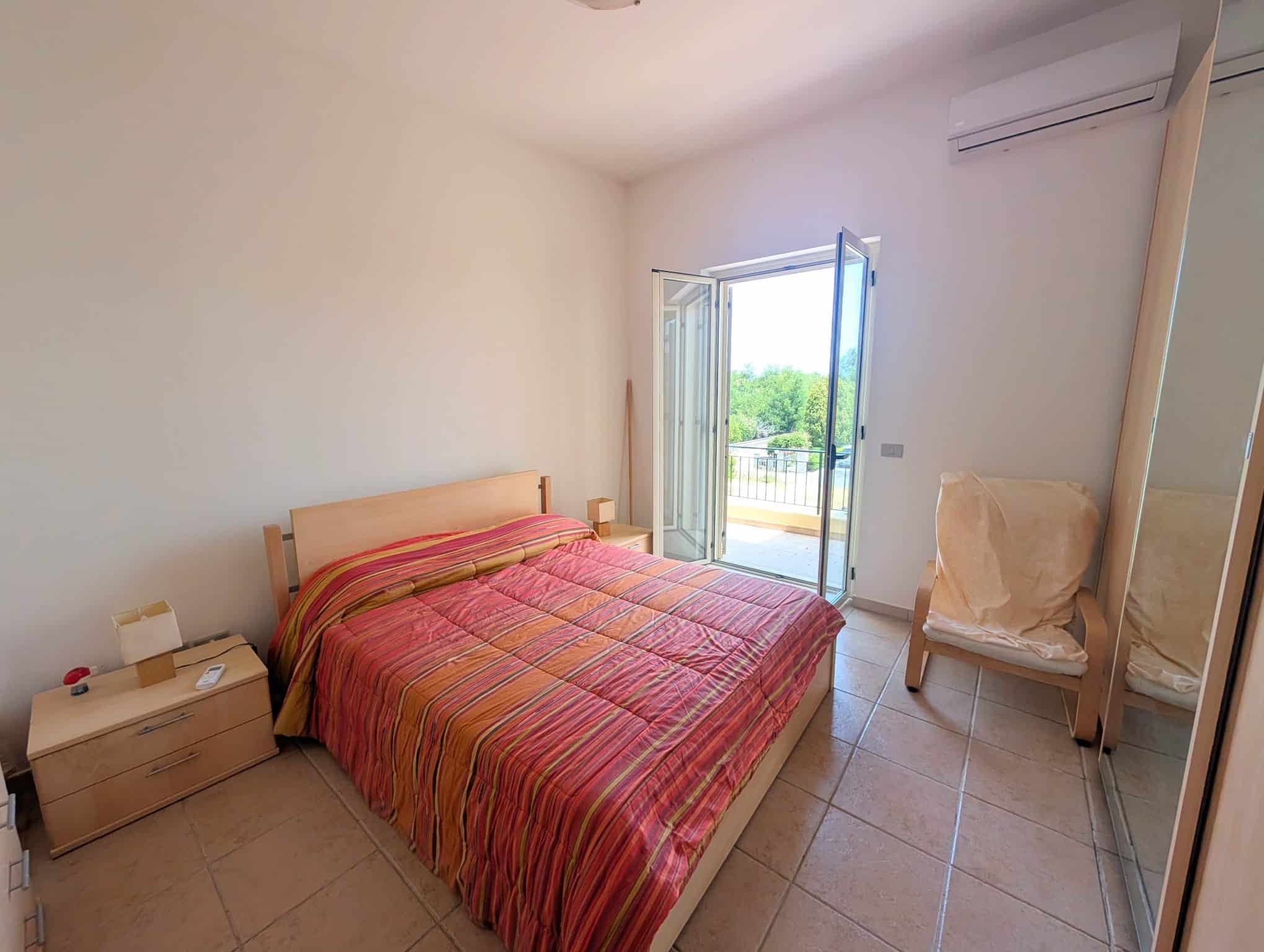Camera da letto luminosa con balcone, letto matrimoniale e armadio a specchio, in un appartamento di Villetta a schiera.