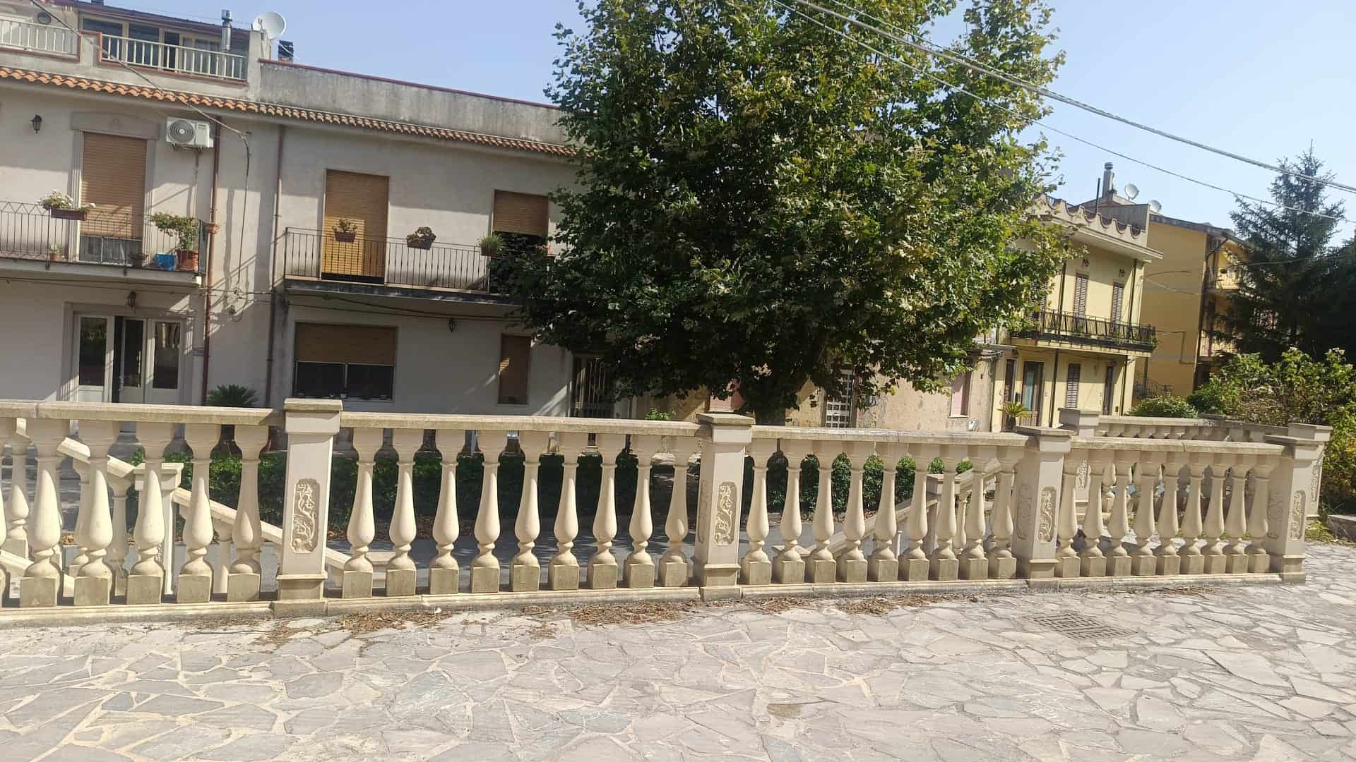 Viale con ringhiera in pietra e alberi, zona residenziale a Rometta, ME.
