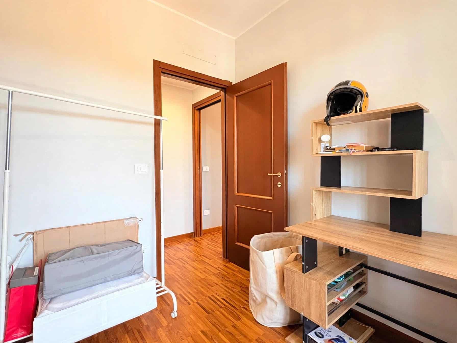 Camera da letto con letto singolo, scrivania e armadietto in legno, ambiente luminoso e accogliente in appartamento a Milazzo.