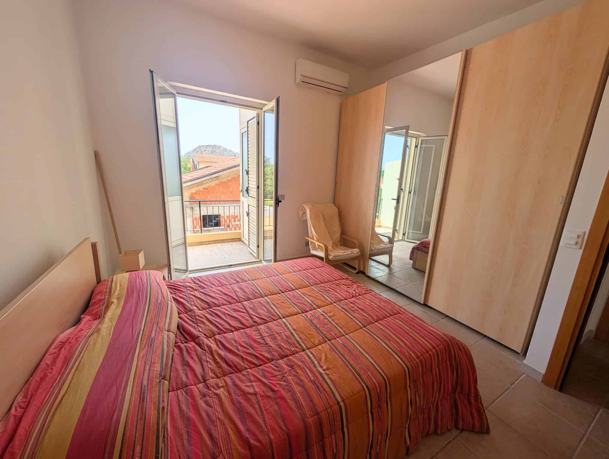 Camera da letto luminosa con balcone, armadio a specchio e arredi moderni, ideale per Villetta a schiera.