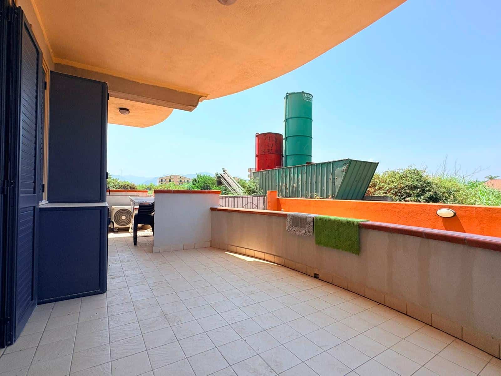 Balcone spazioso con vista su impianto di stoccaggio e area verde, ideale per relax e svago.