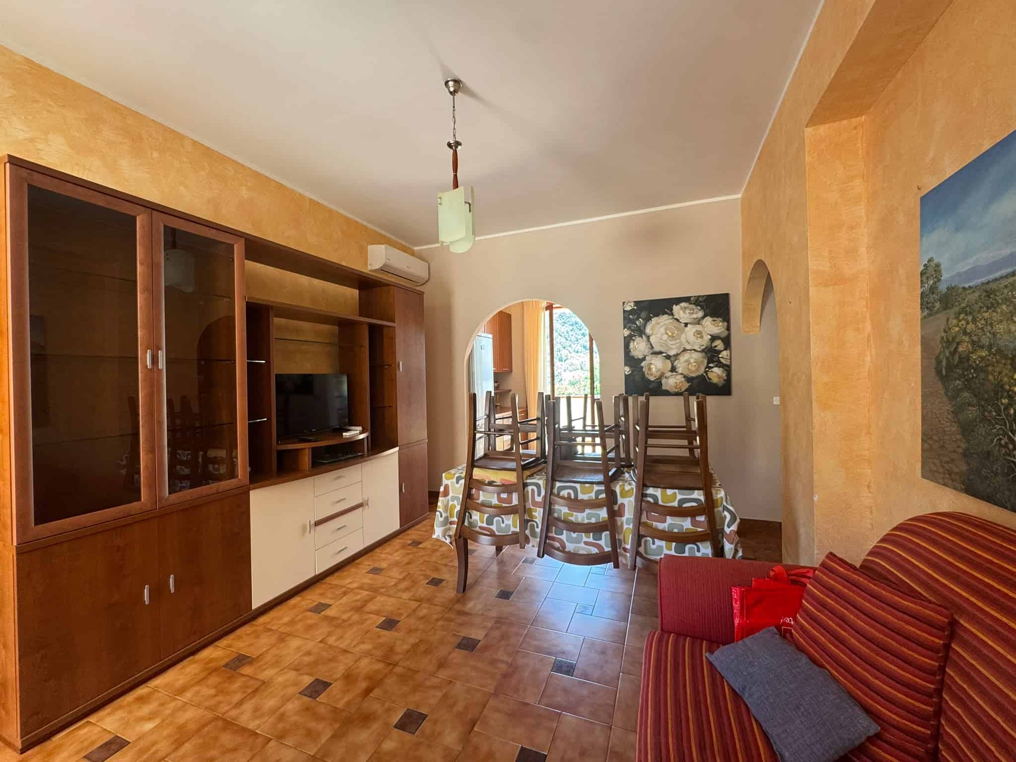 Interno soggiorno di una villa in vendita a Milazzo con mobili in legno e divano rosso.