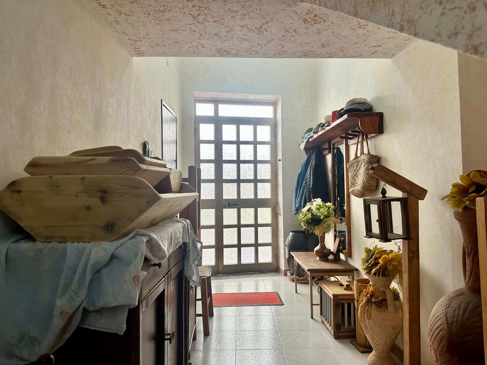Ingresso di un appartamento con porta in vetro e decorazioni di stile rustico e vintage.