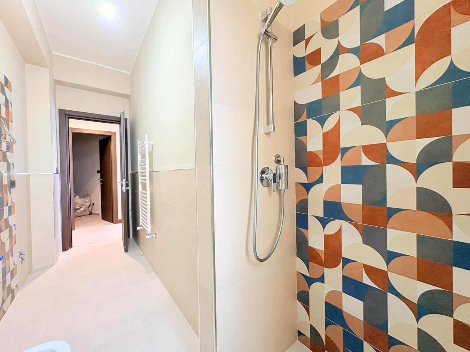 Doccia moderna con parete decorativa geometrica in toni caldi e freddi, in appartamento in vendita a Milazzo.