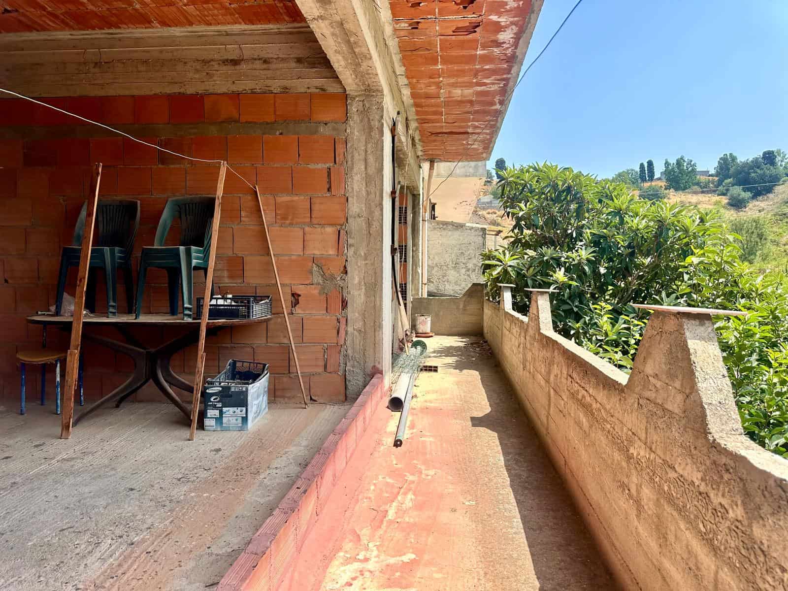 Balcone di un edificio in costruzione con vista su natura e cielo azzurro, materiali da costruzione visibili.
