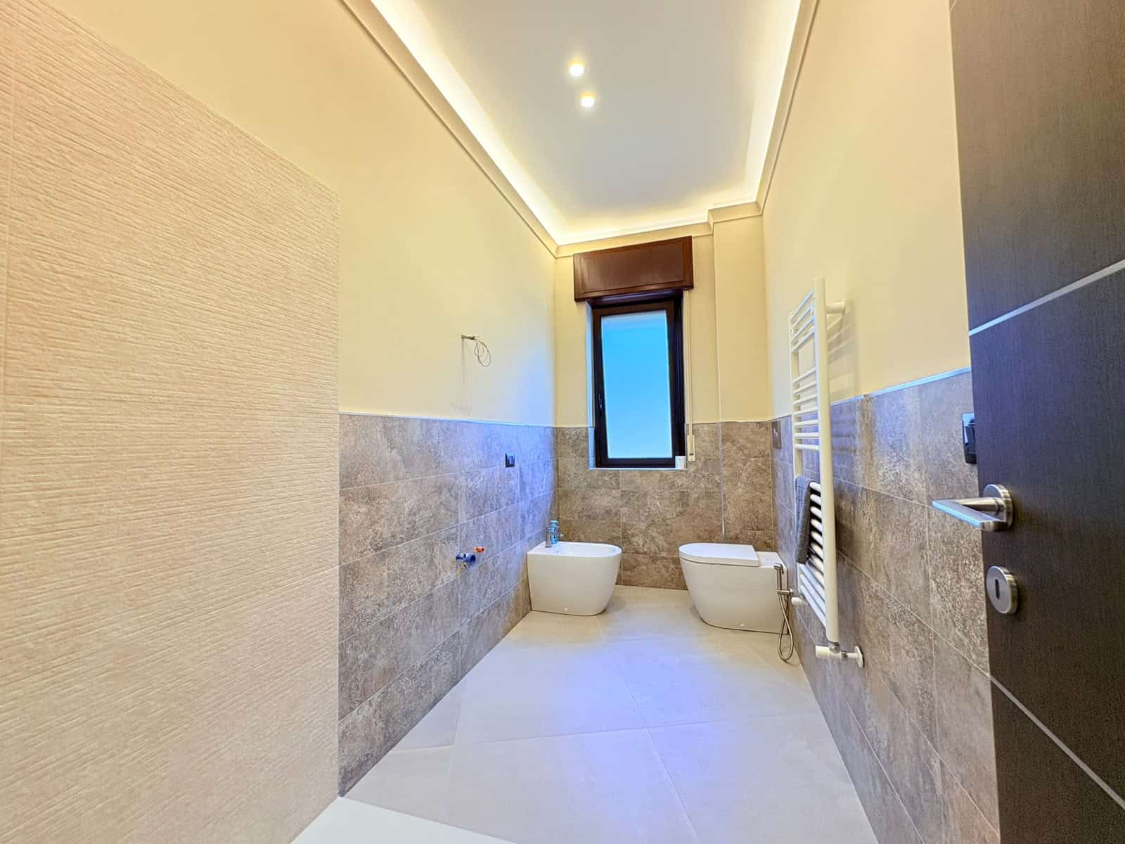 Bagno moderno con finestra, sanitari bianchi e riscaldamento a radiatore in un appartamento in vendita a Milazzo.